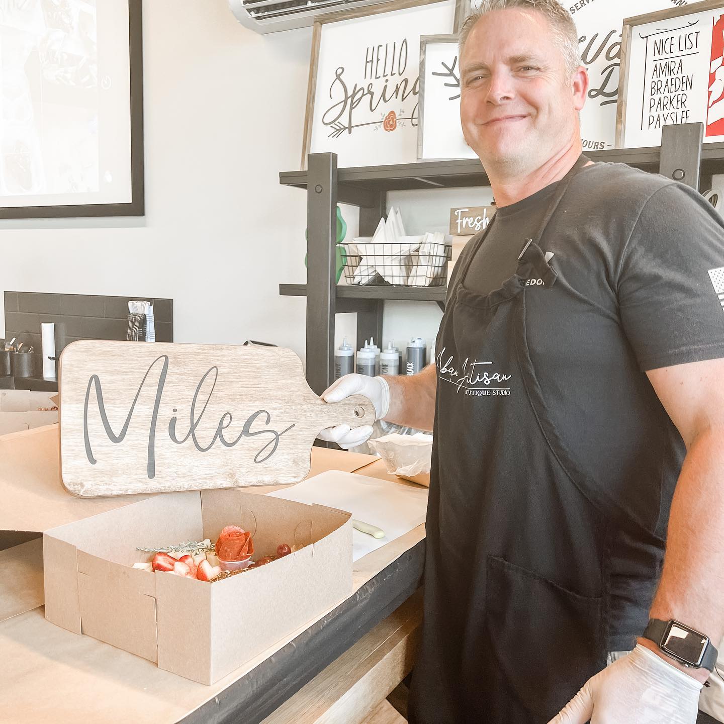 A man in an apron is standing next to a box of strawberries and a sign that says miles.