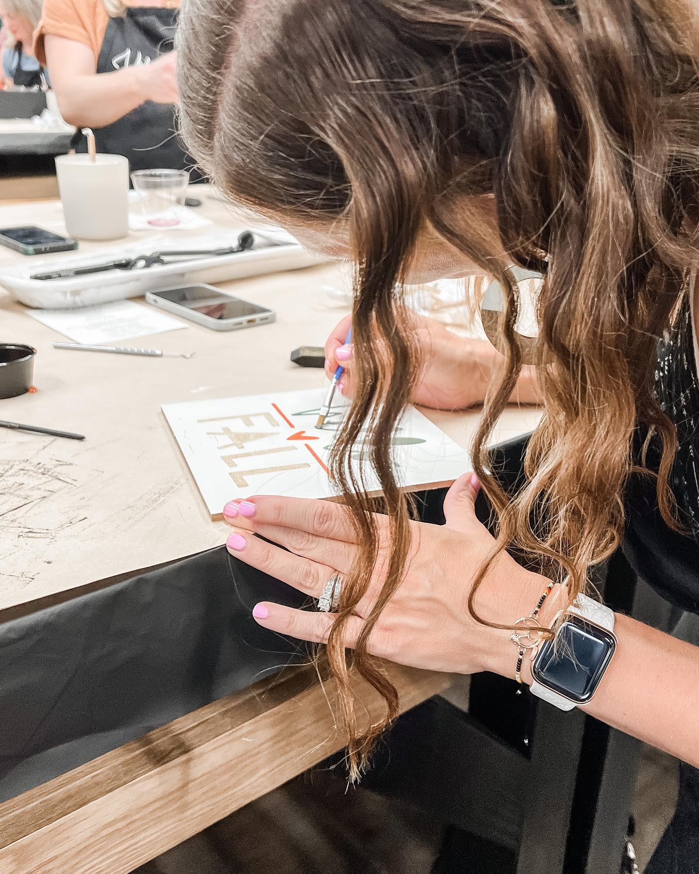A woman is sitting at a table writing on a piece of paper.
