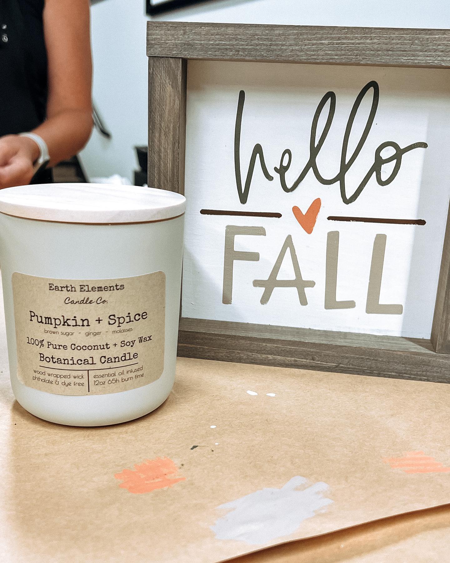 A candle is sitting next to a sign that says hello fall