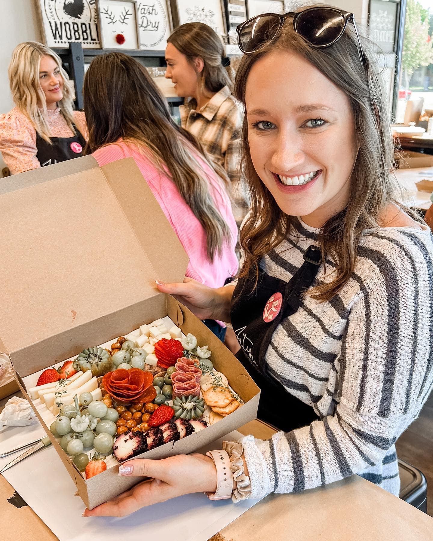 A woman is holding a box of food and smiling.