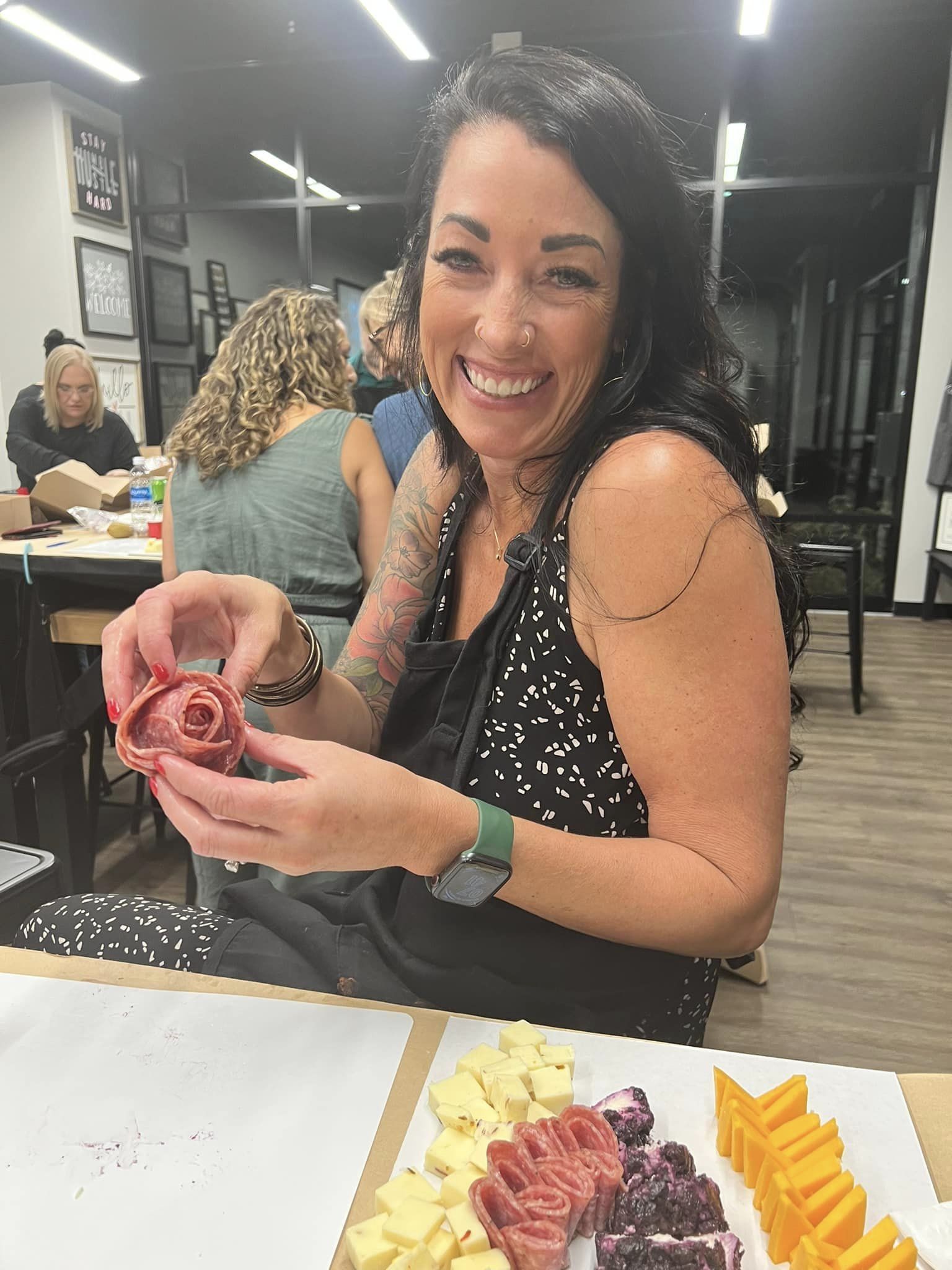 A woman is sitting at a table with a plate of food and smiling.