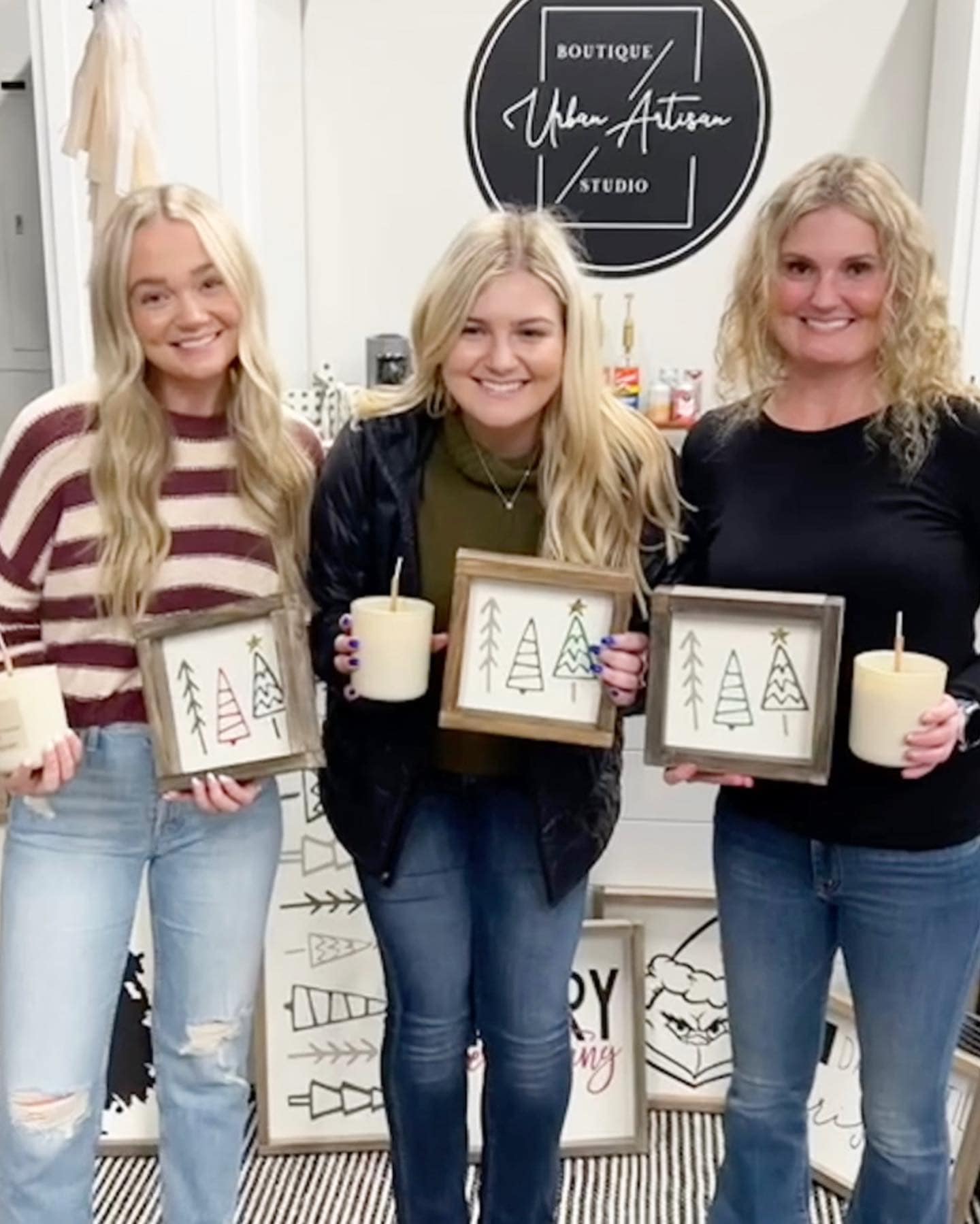 Three women are standing next to each other holding candles and framed pictures.
