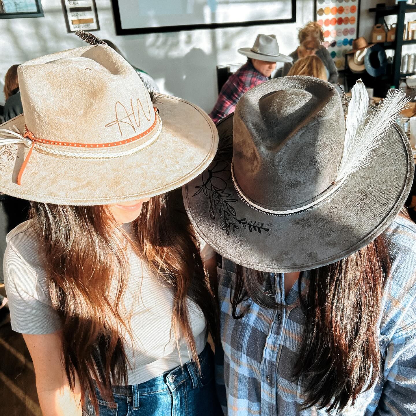 Two women wearing cowboy hats are standing next to each other.
