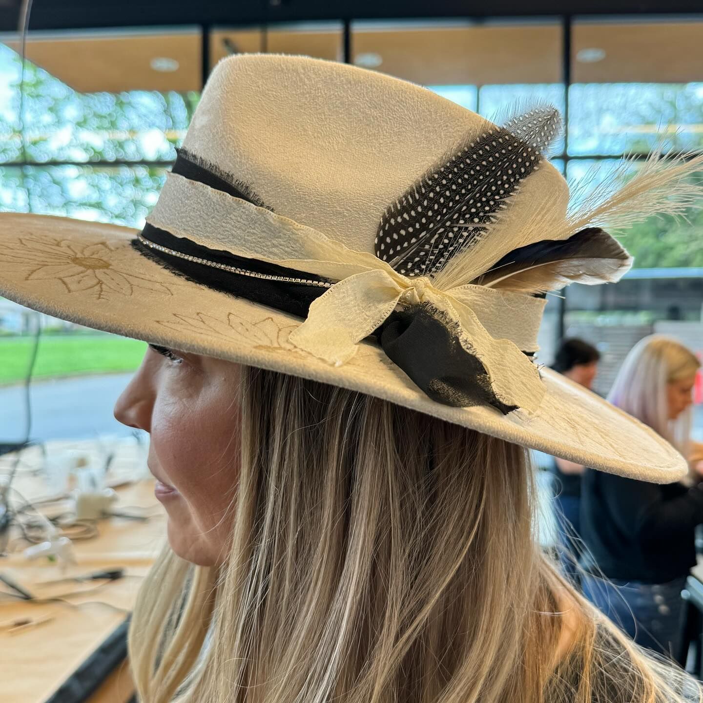A woman wearing a white hat with feathers on it