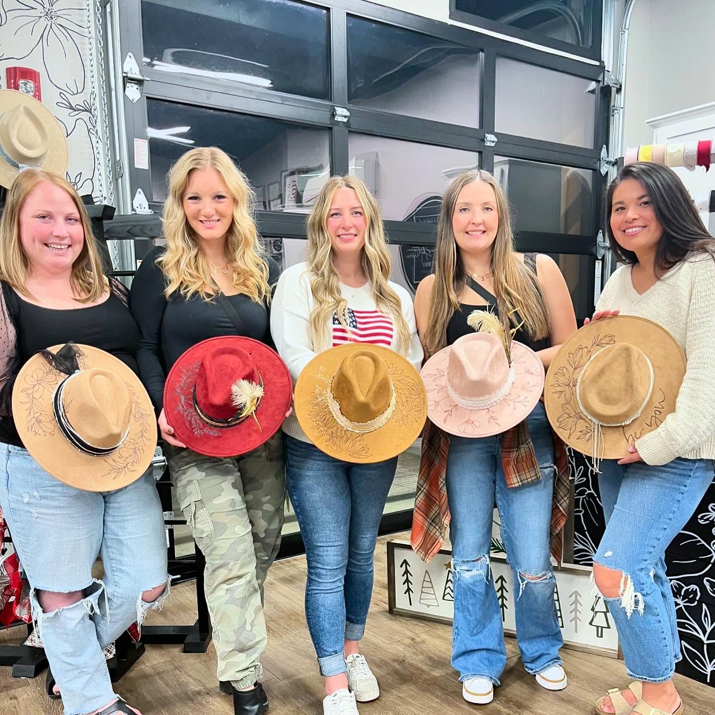 A group of women are standing next to each other holding hats.