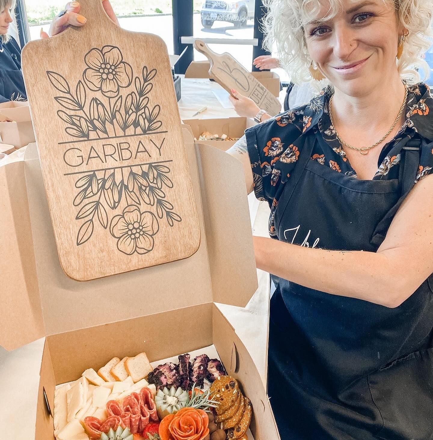 A woman is holding a cutting board that says garibay