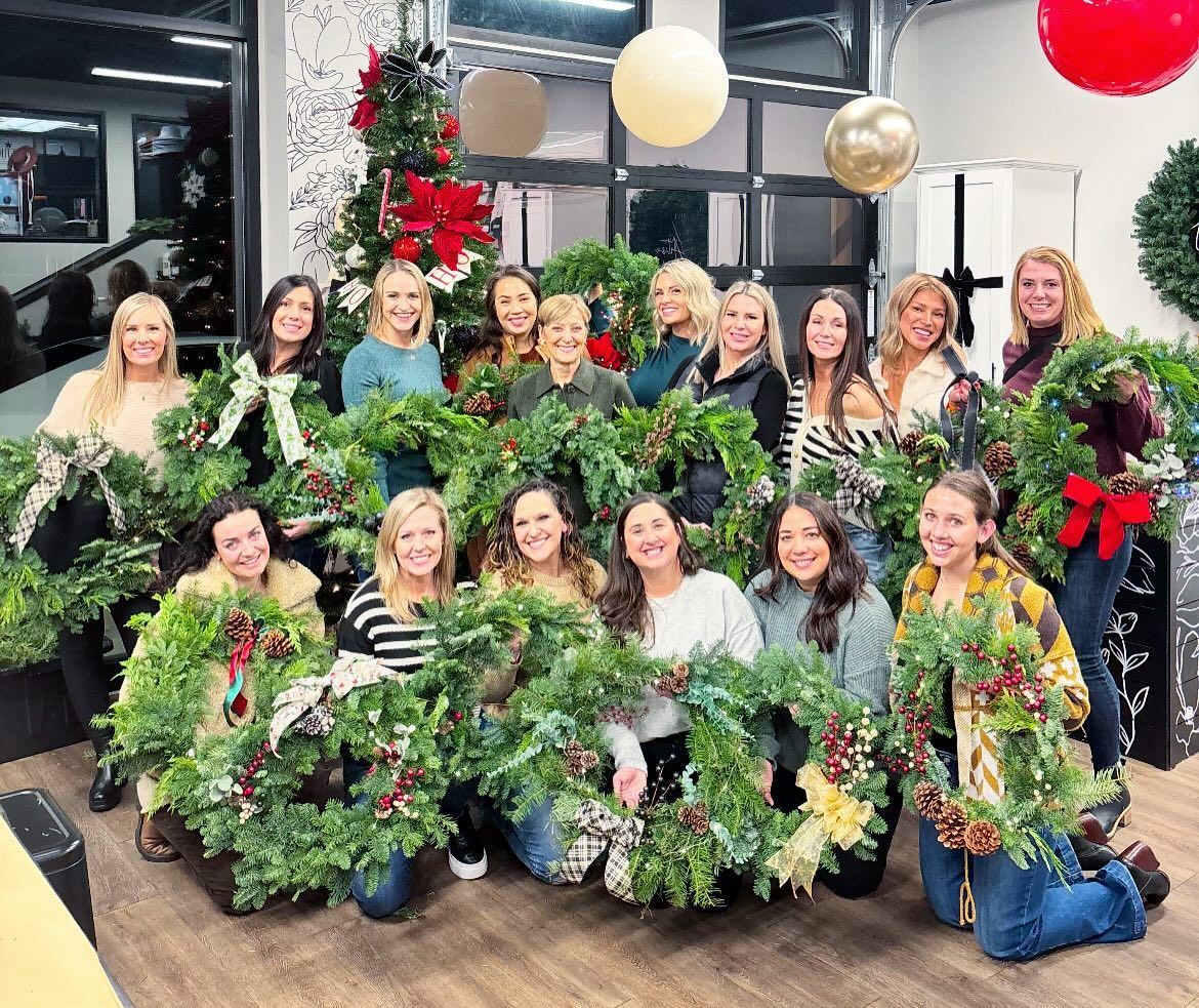 A group of women are holding christmas wreaths in a room.