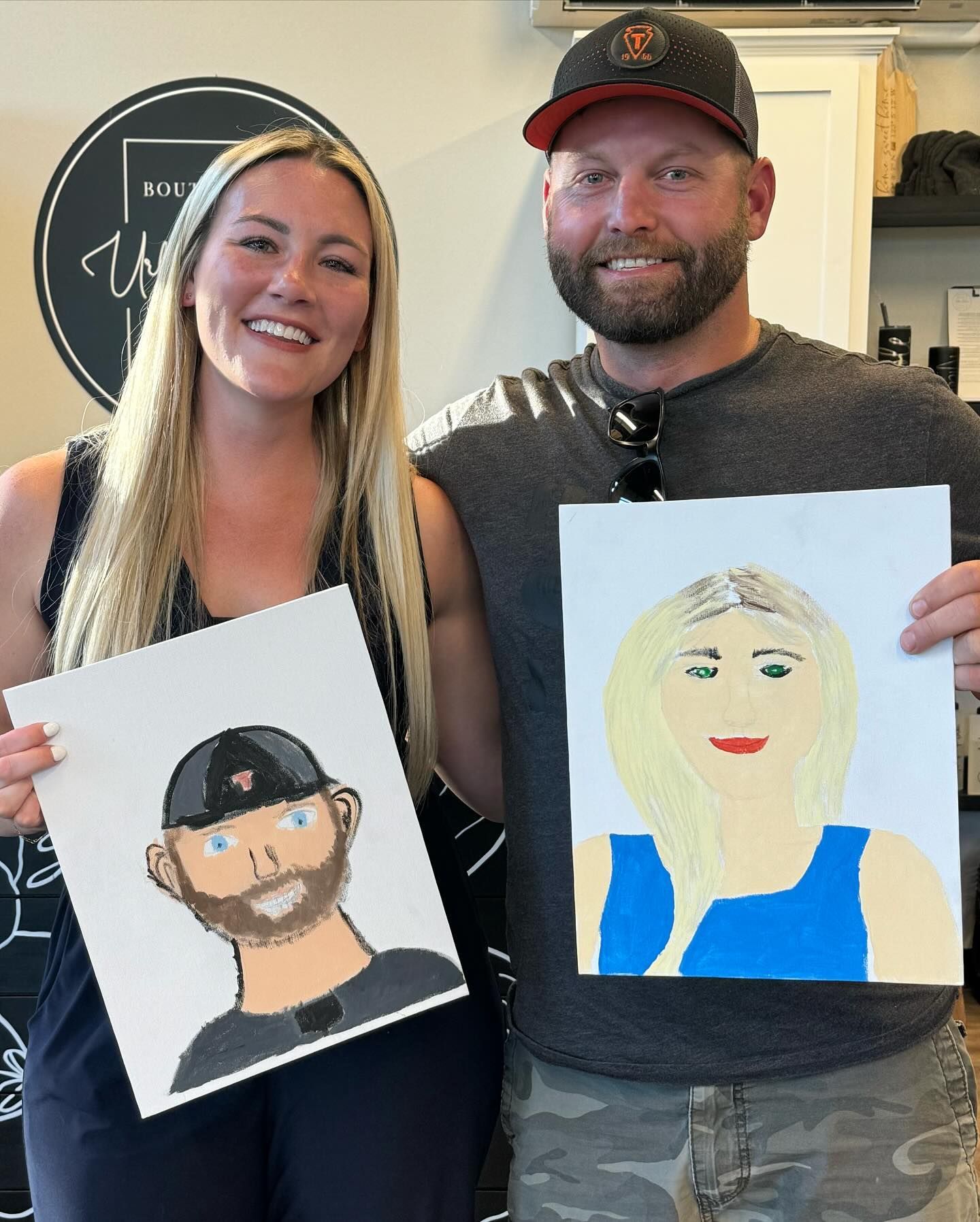 A man and a woman are holding paintings of themselves
