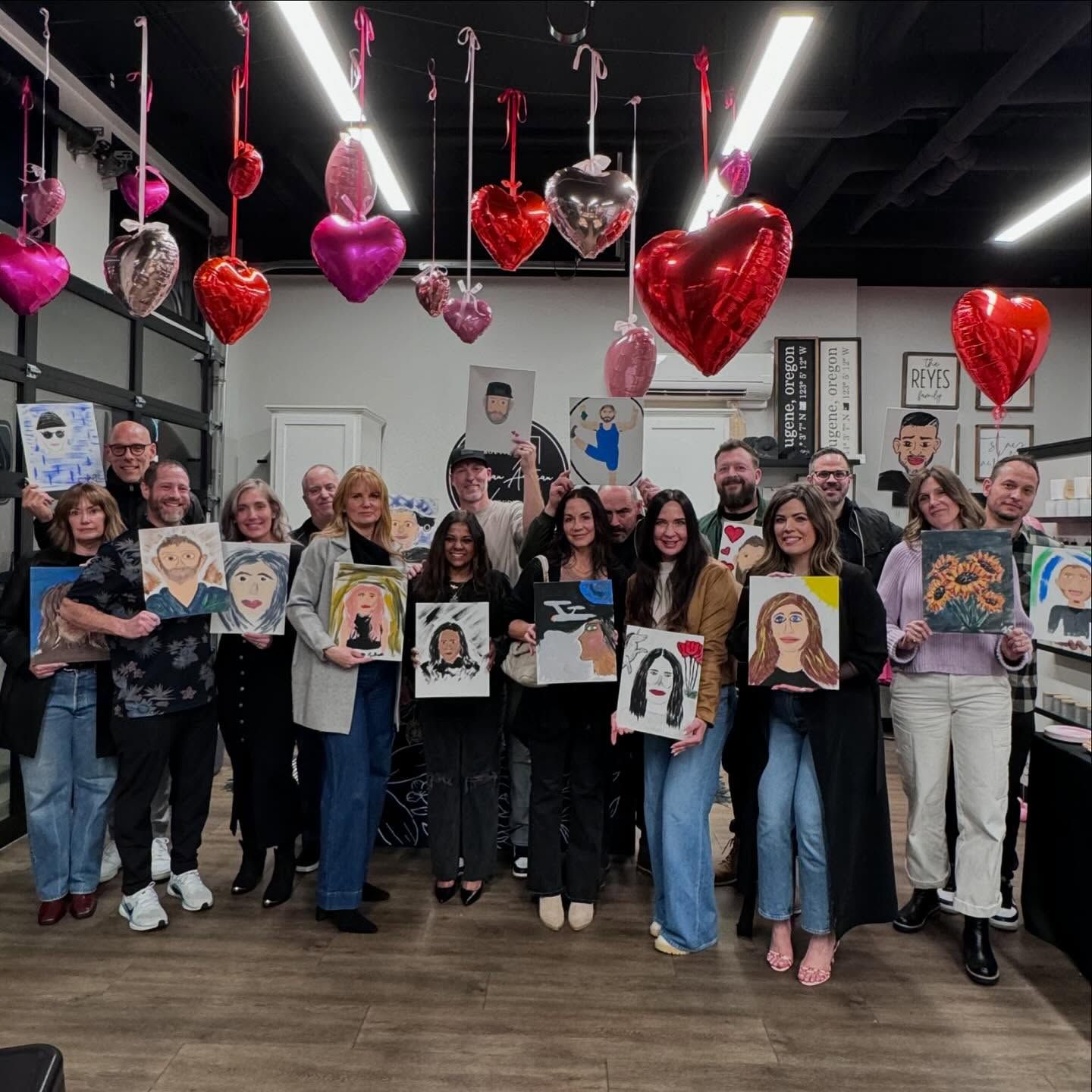 A group of people are posing for a picture in a room with balloons and hearts hanging from the ceiling.