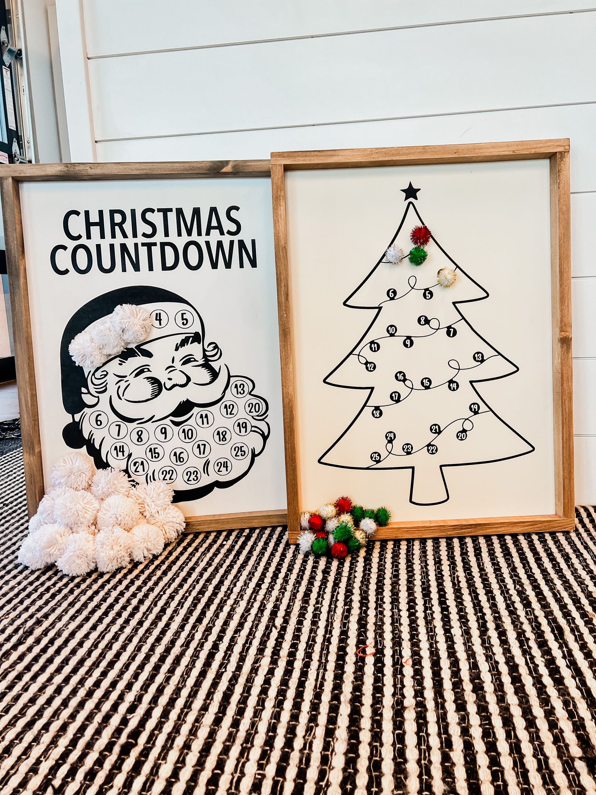 A christmas countdown sign and a christmas tree sign are sitting on a striped rug.