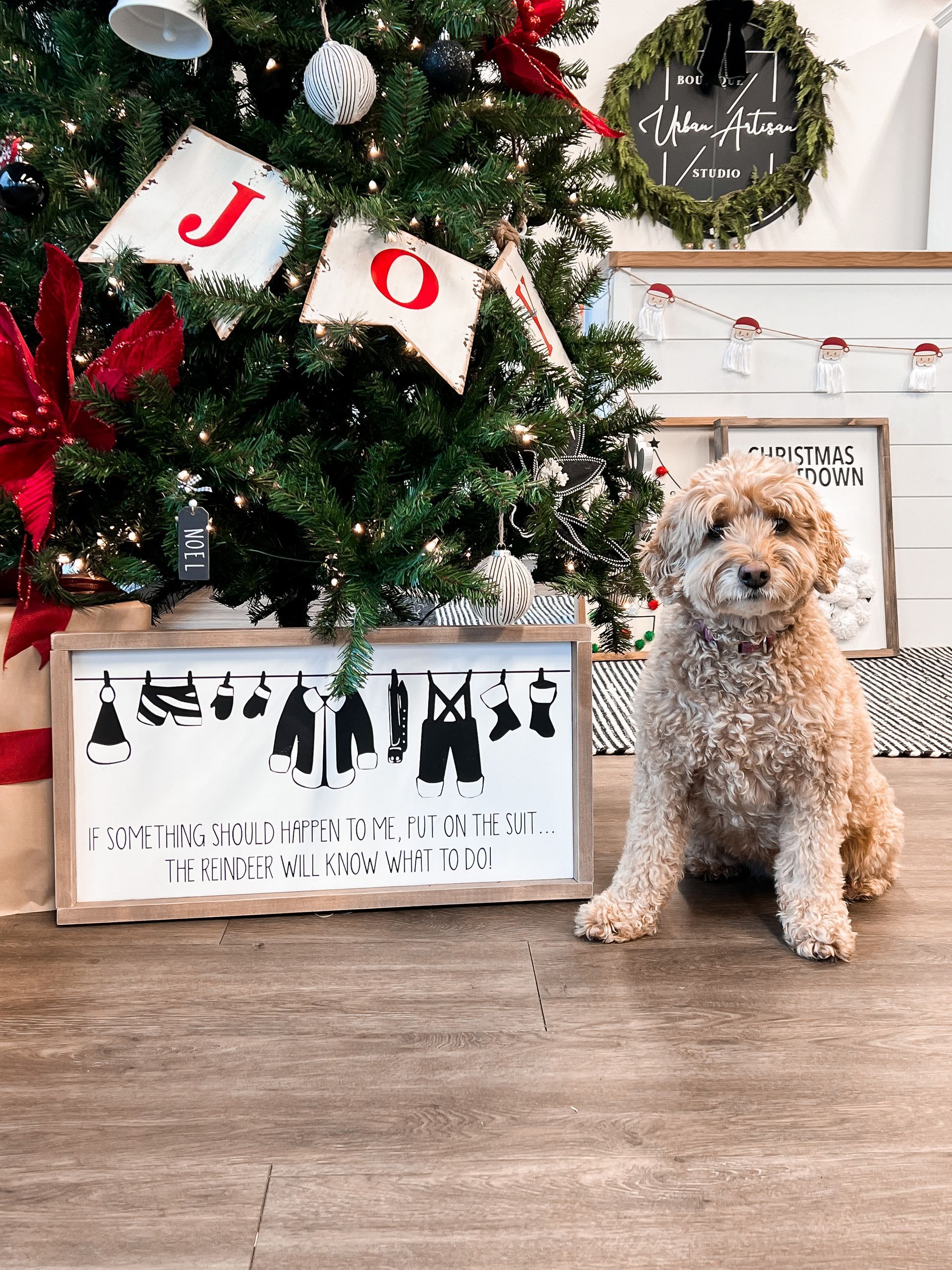 A small dog is sitting in front of a christmas tree.