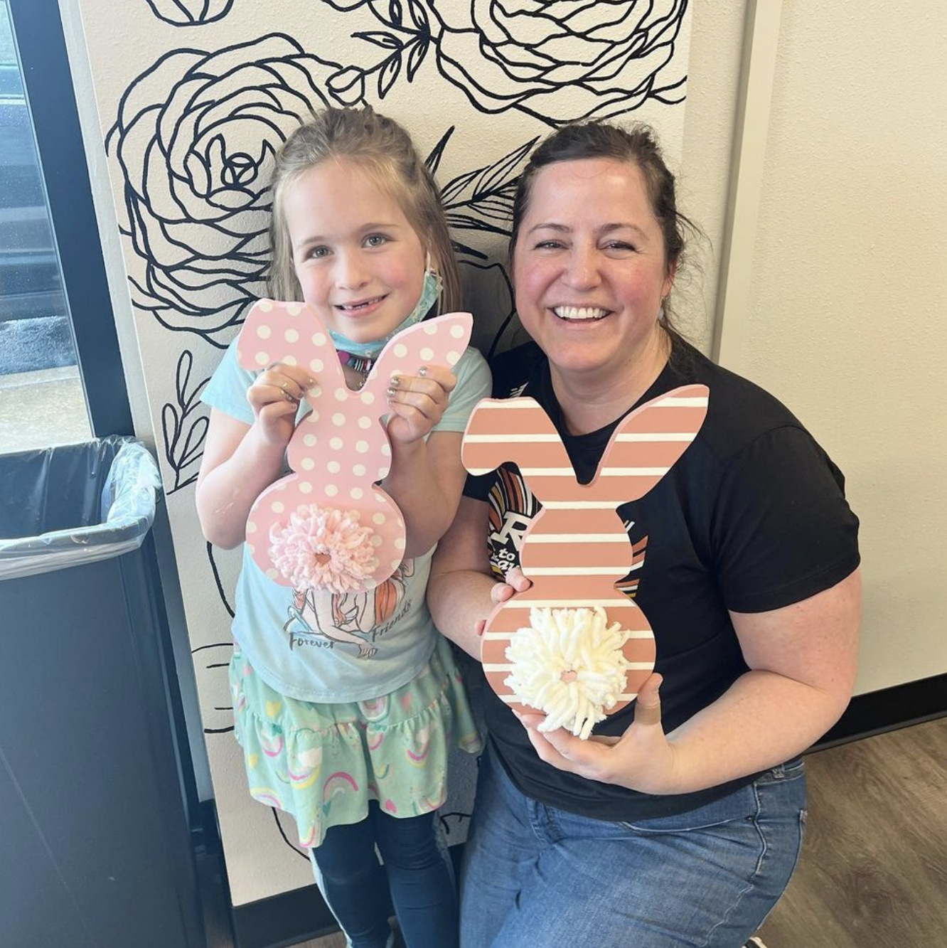 A woman and a little girl are holding easter bunny decorations.