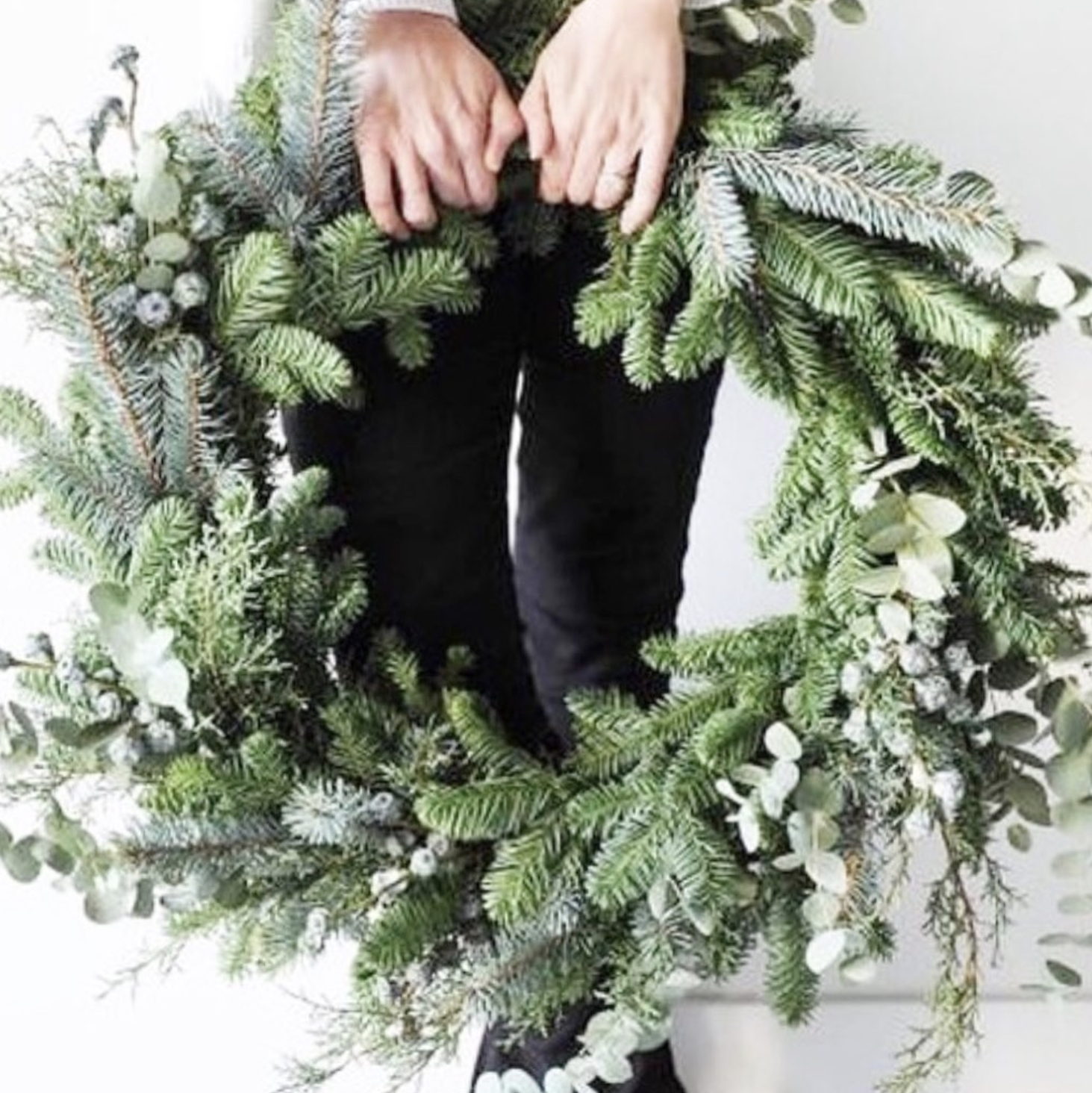 A person is holding a christmas wreath in their hands