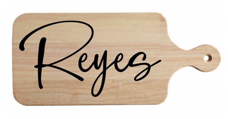 A wooden cutting board with the name reyes written on it