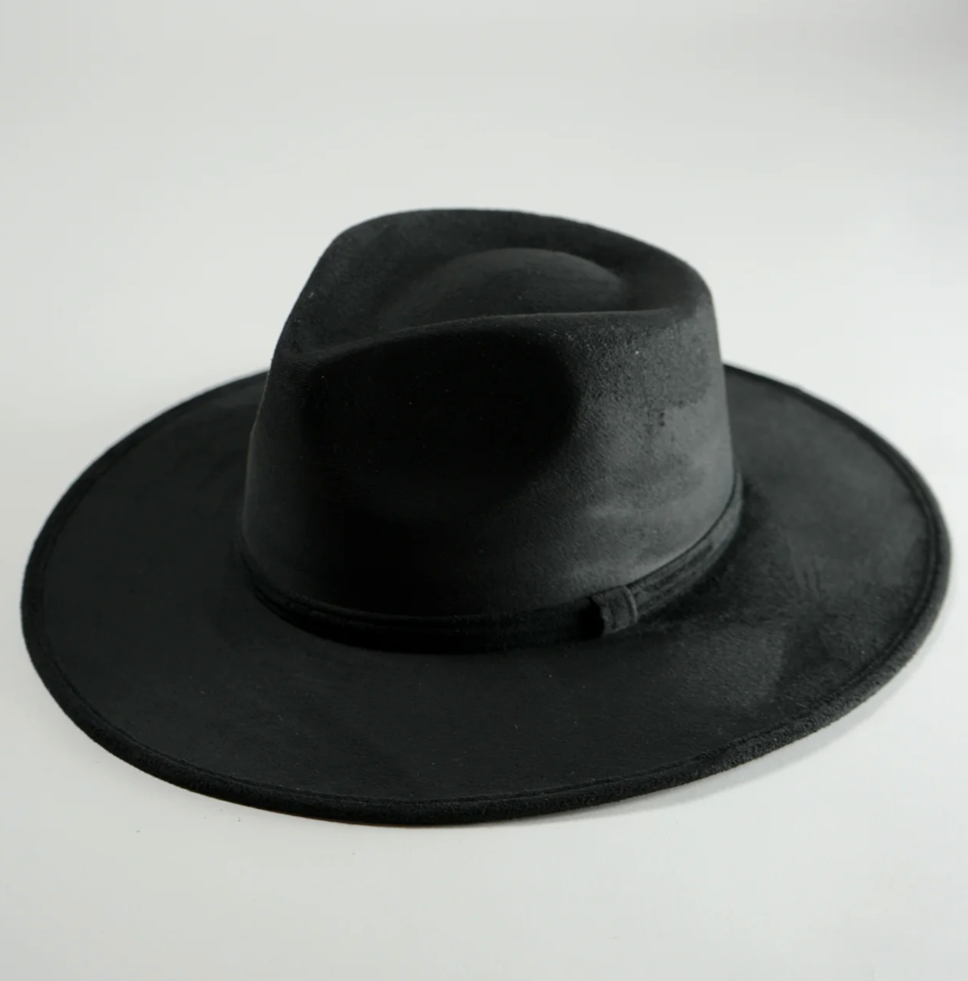 A black fedora hat is sitting on a white surface