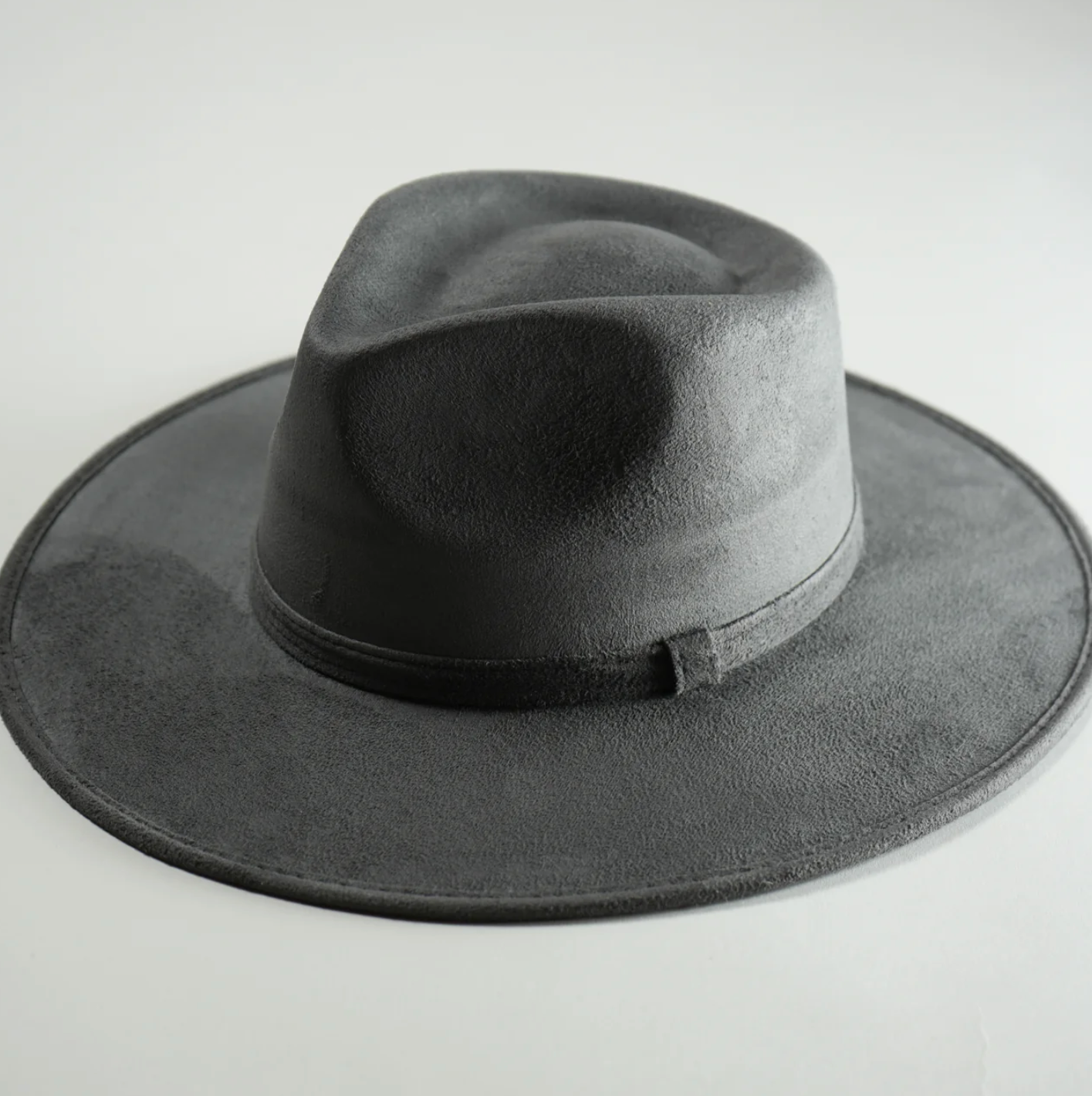 A black fedora hat is sitting on a white surface.