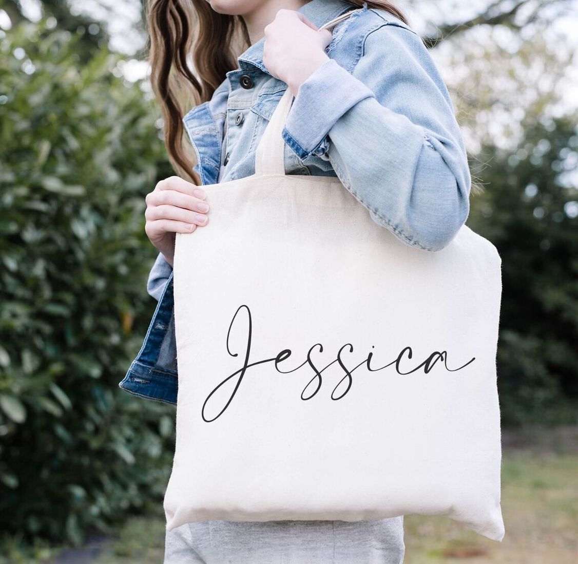 A woman is holding a tote bag with the name jessica on it.