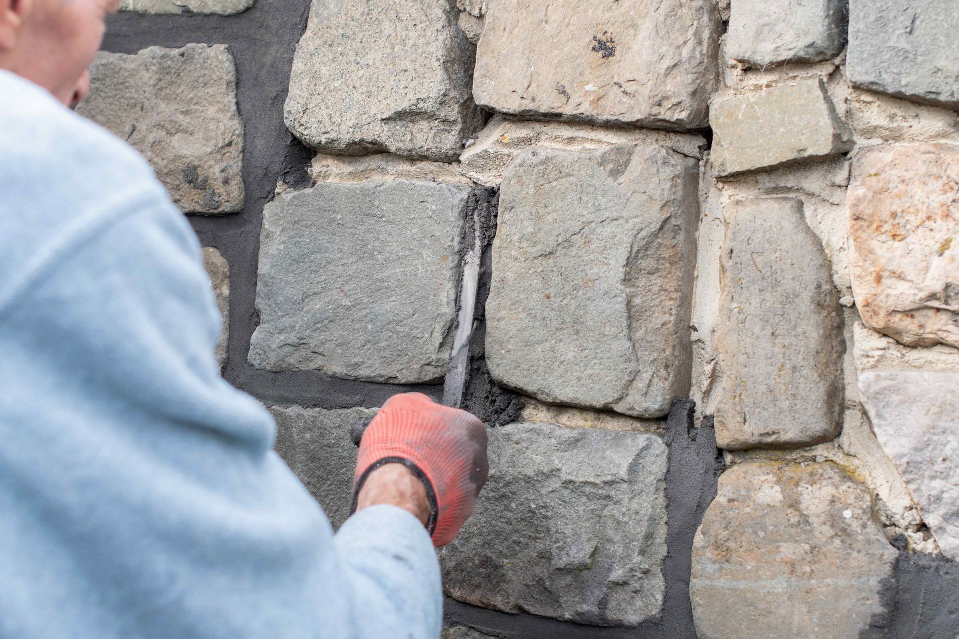 Worker troweling mortar between stone wall blocks