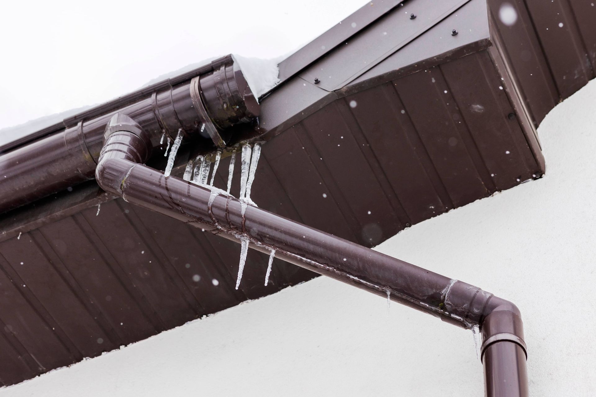 Icicles hanging from brown roof gutters on a snowy day