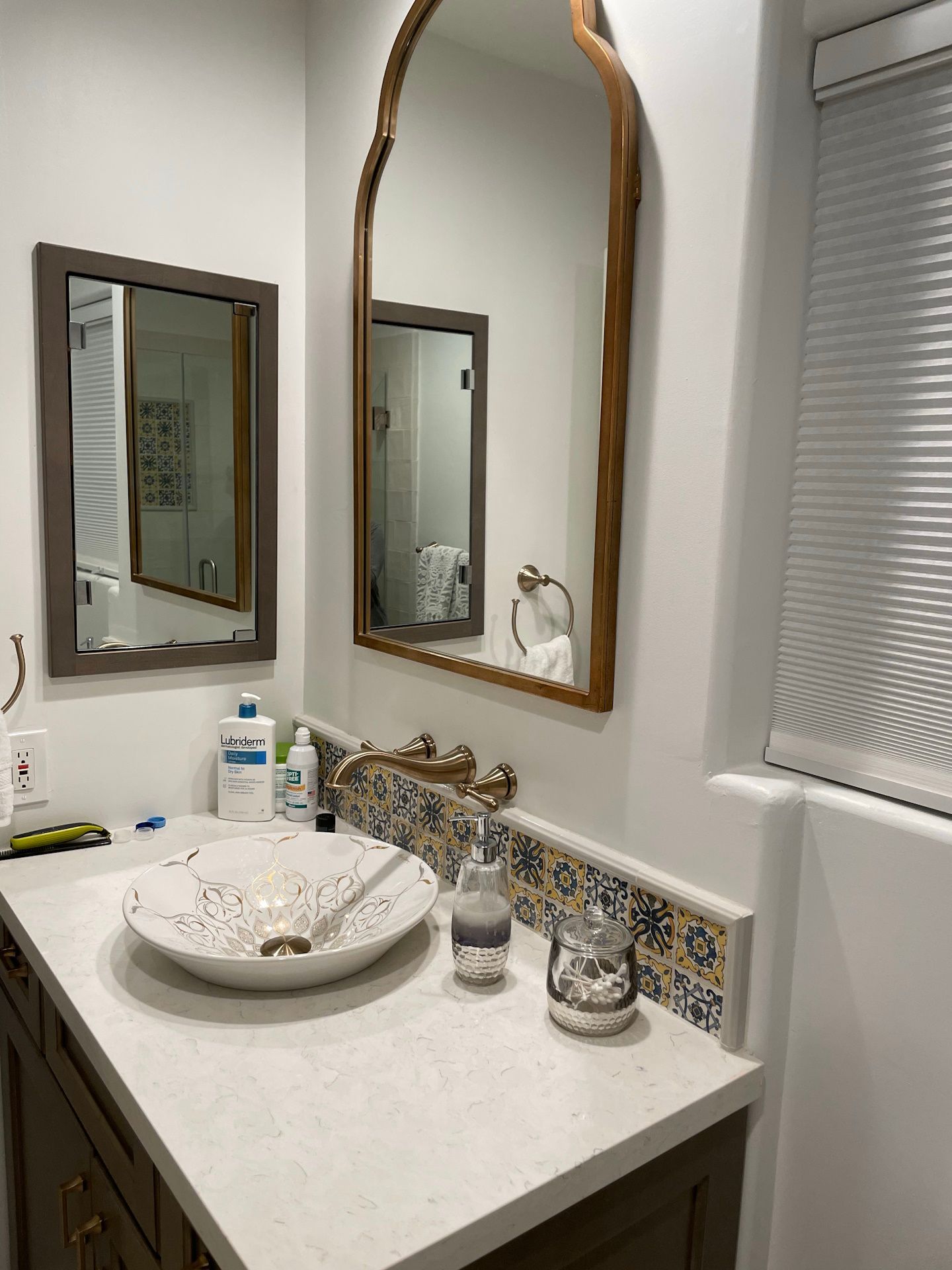A bathroom with a sink , mirrors and a window.
