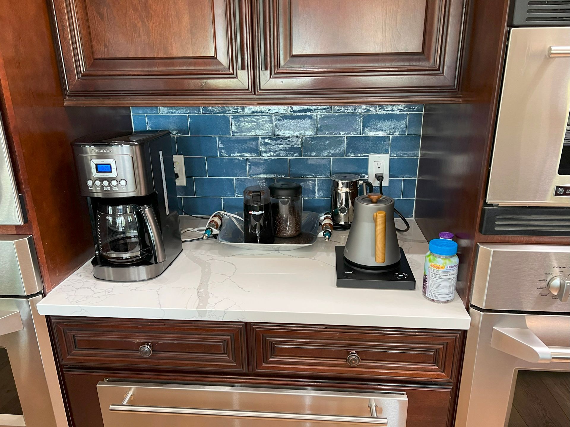 A kitchen counter with a coffee maker and a kettle on it.