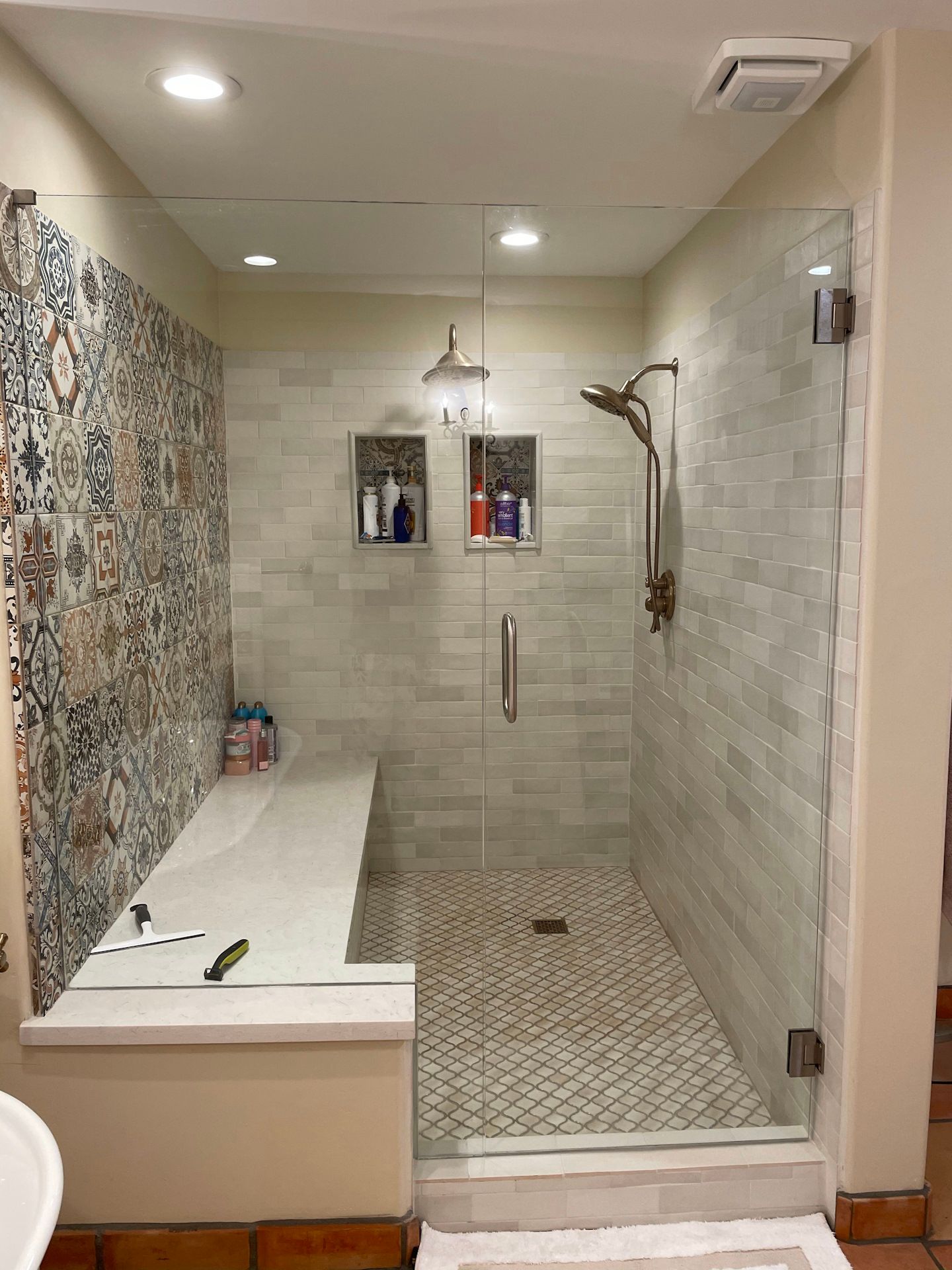 A bathroom with a walk in shower and a bench.