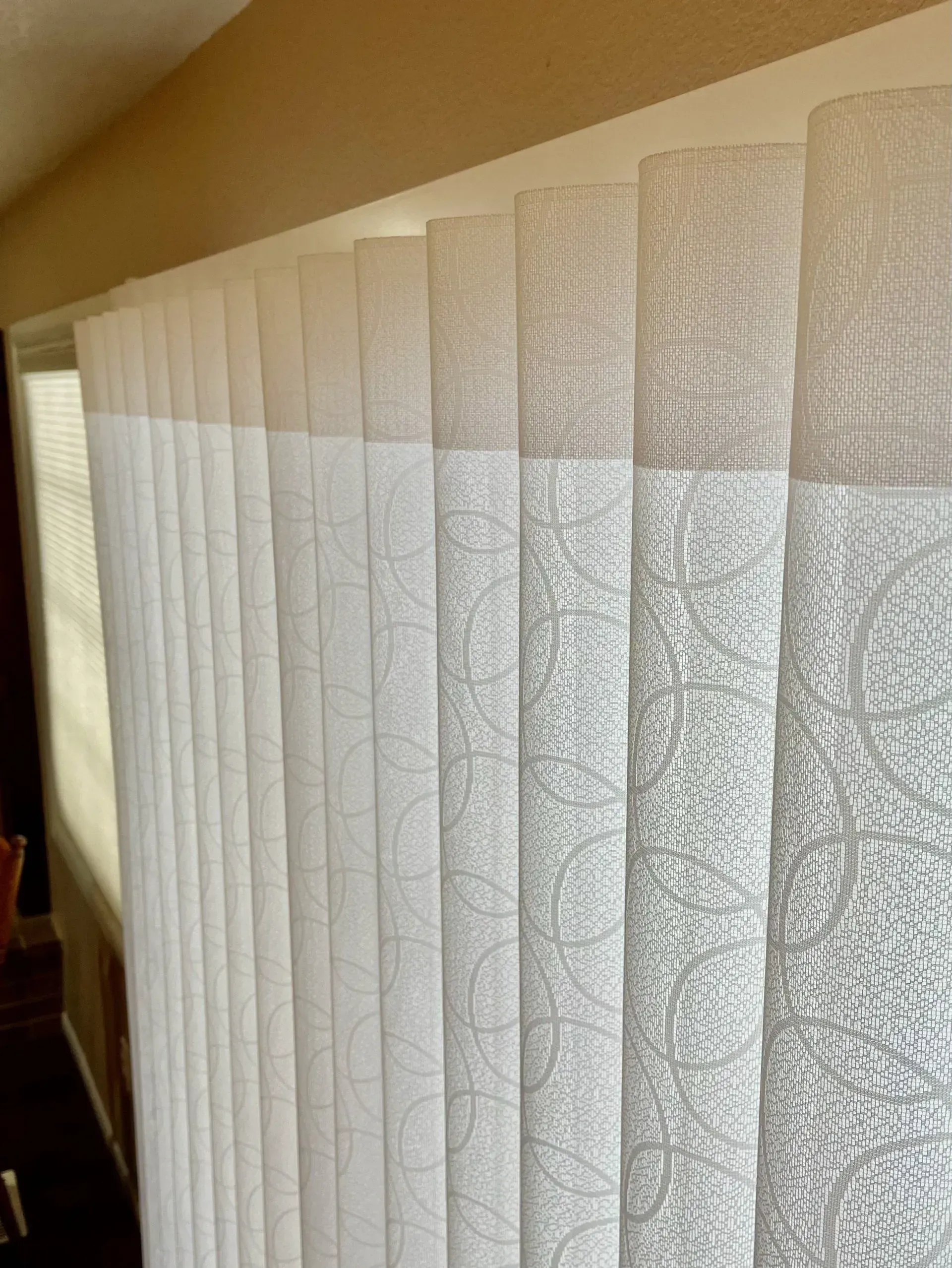 A close up of a row of white vertical blinds on a window.