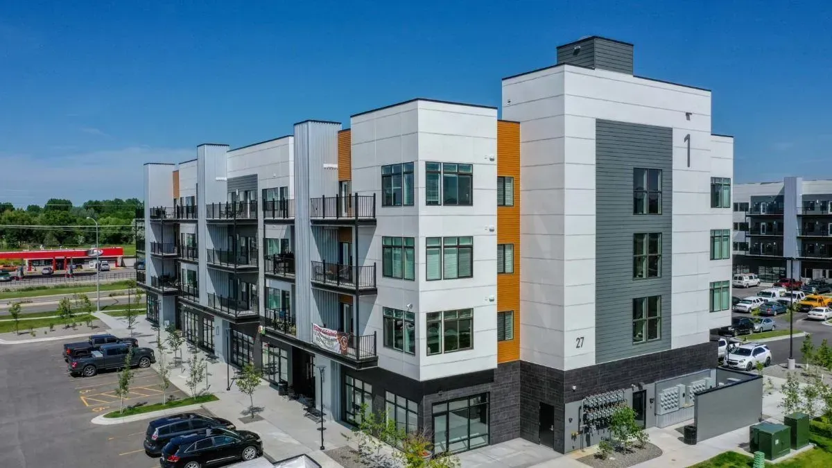 An aerial view of a large apartment building with cars parked in front of it.