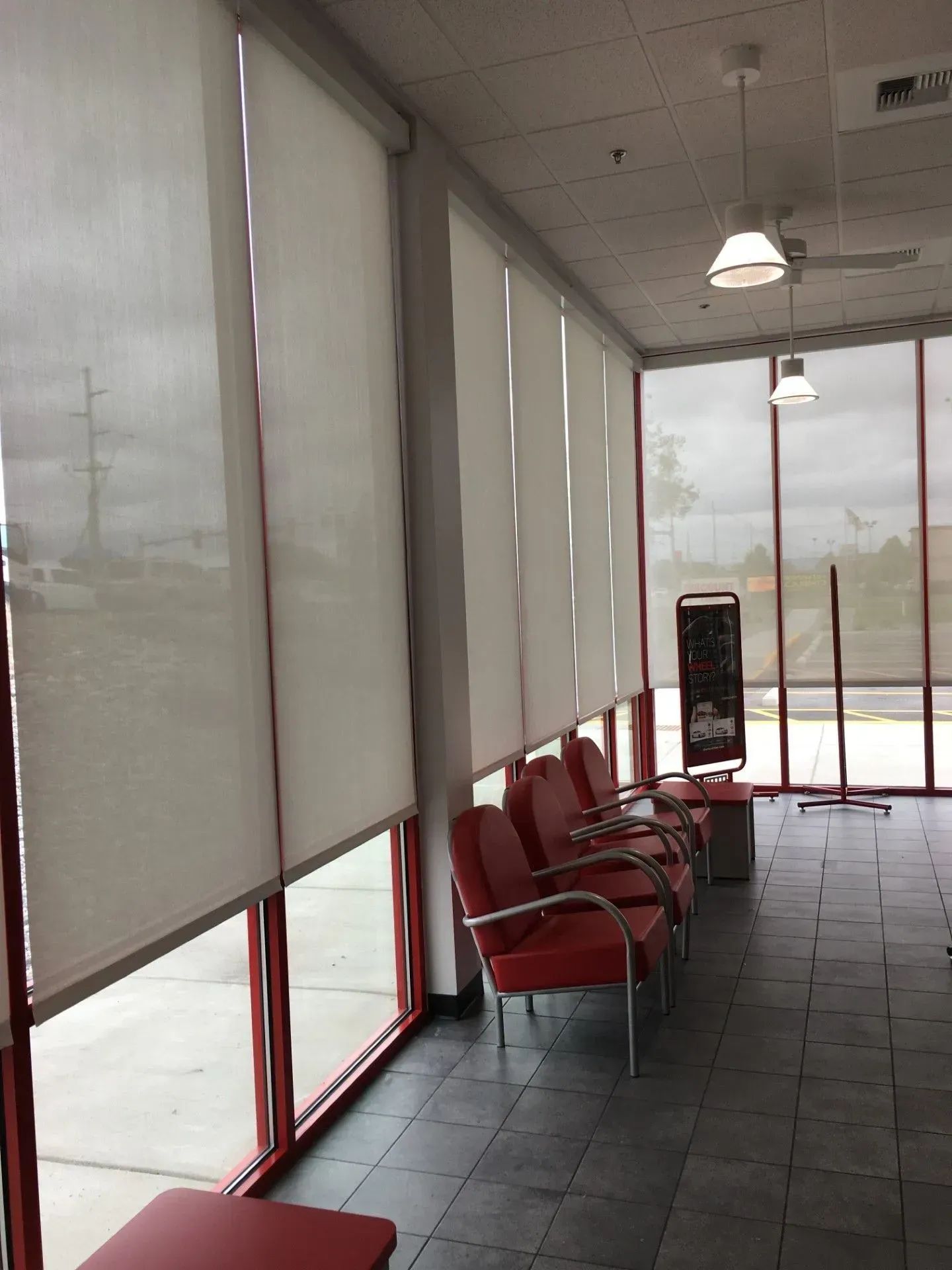 A waiting room with red chairs and white blinds