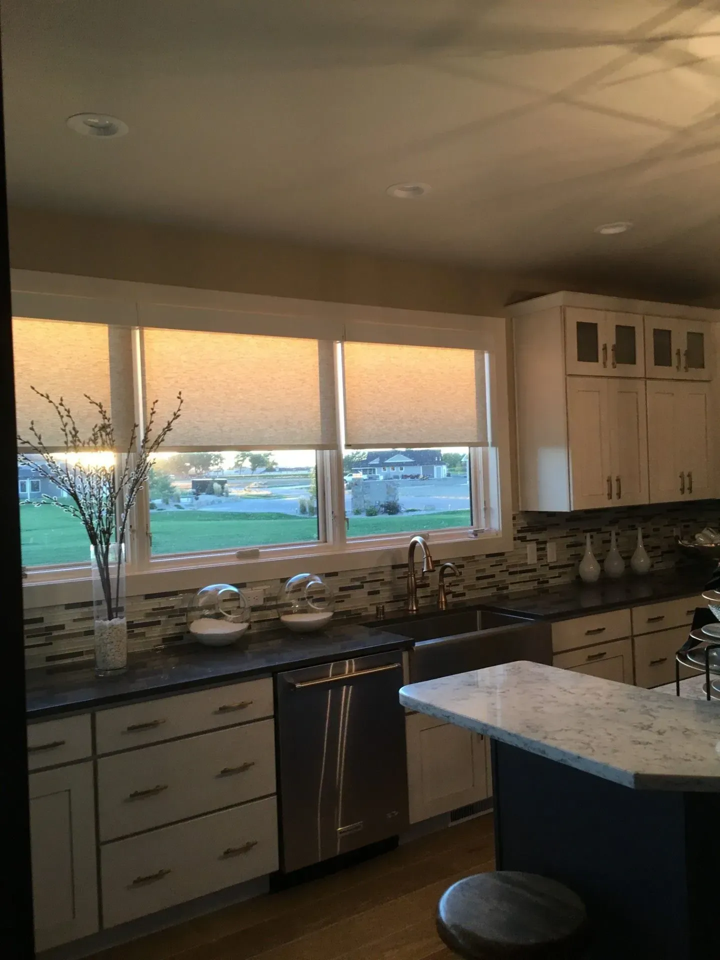 A kitchen with white cabinets, stainless steel appliances and a large island.