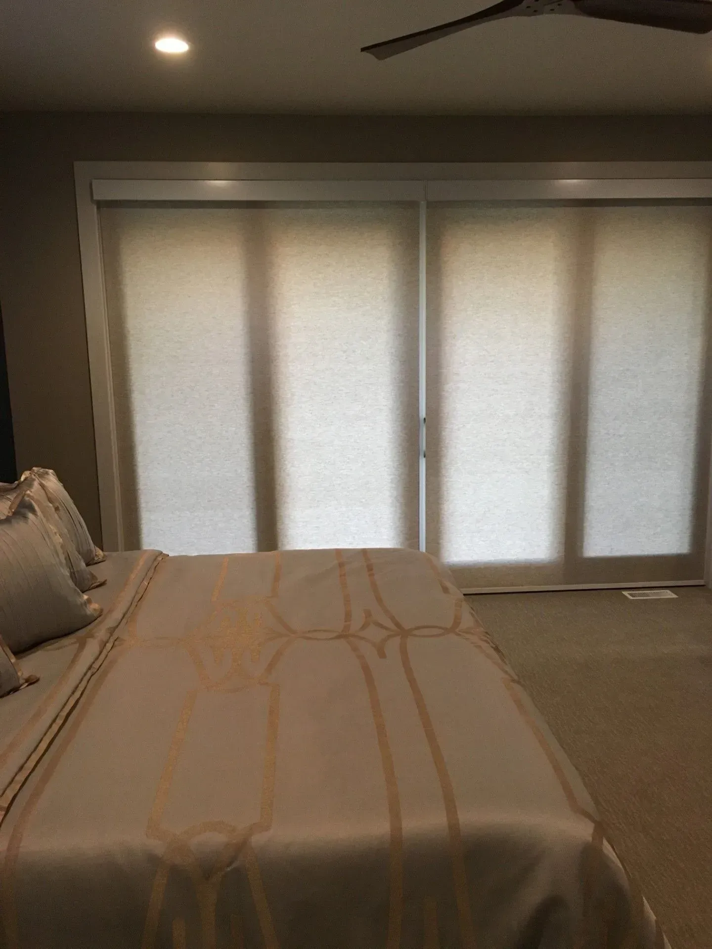 A bedroom with a bed, sliding glass doors, and a ceiling fan.
