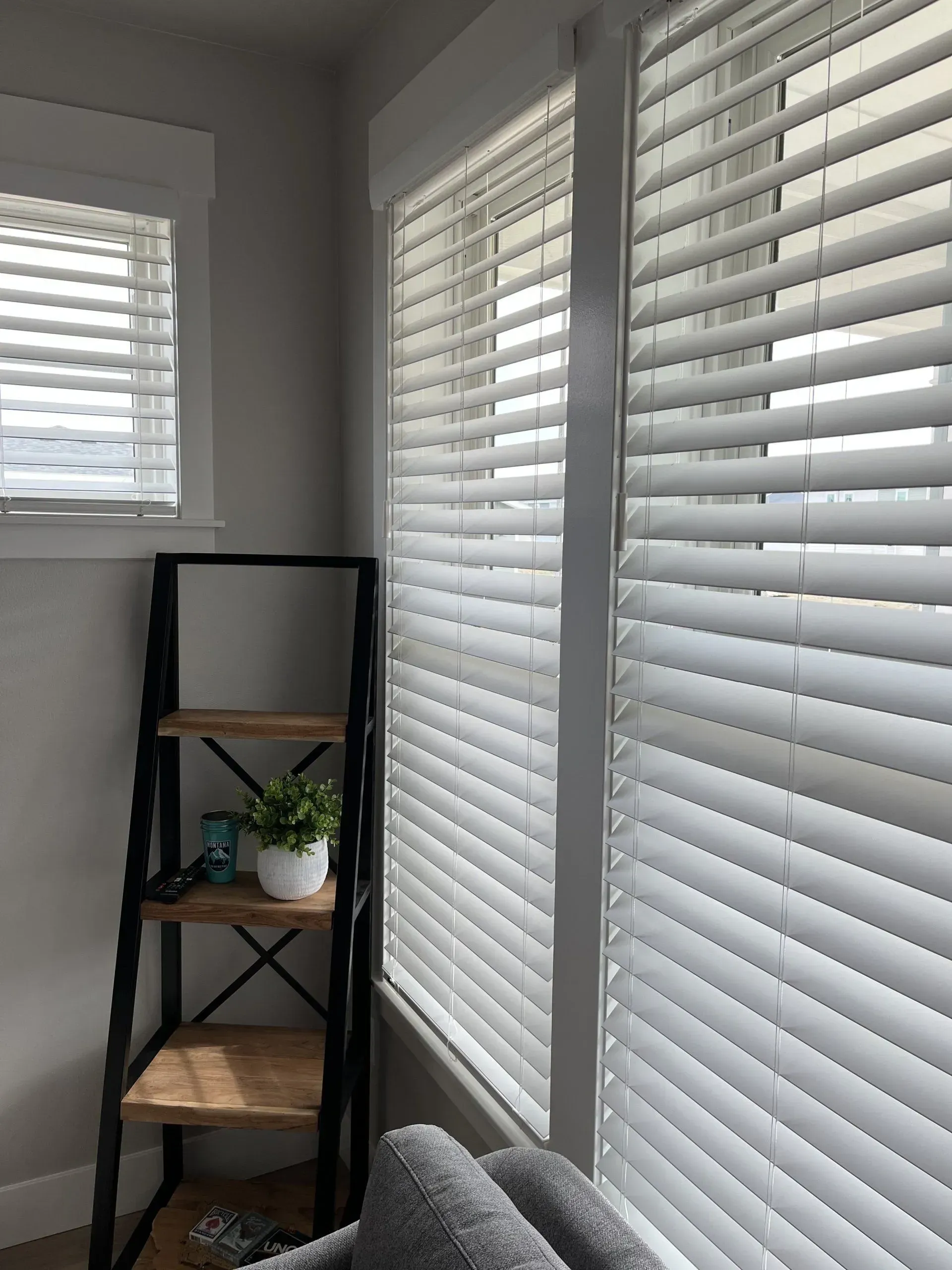 A living room with white blinds and a bookshelf.