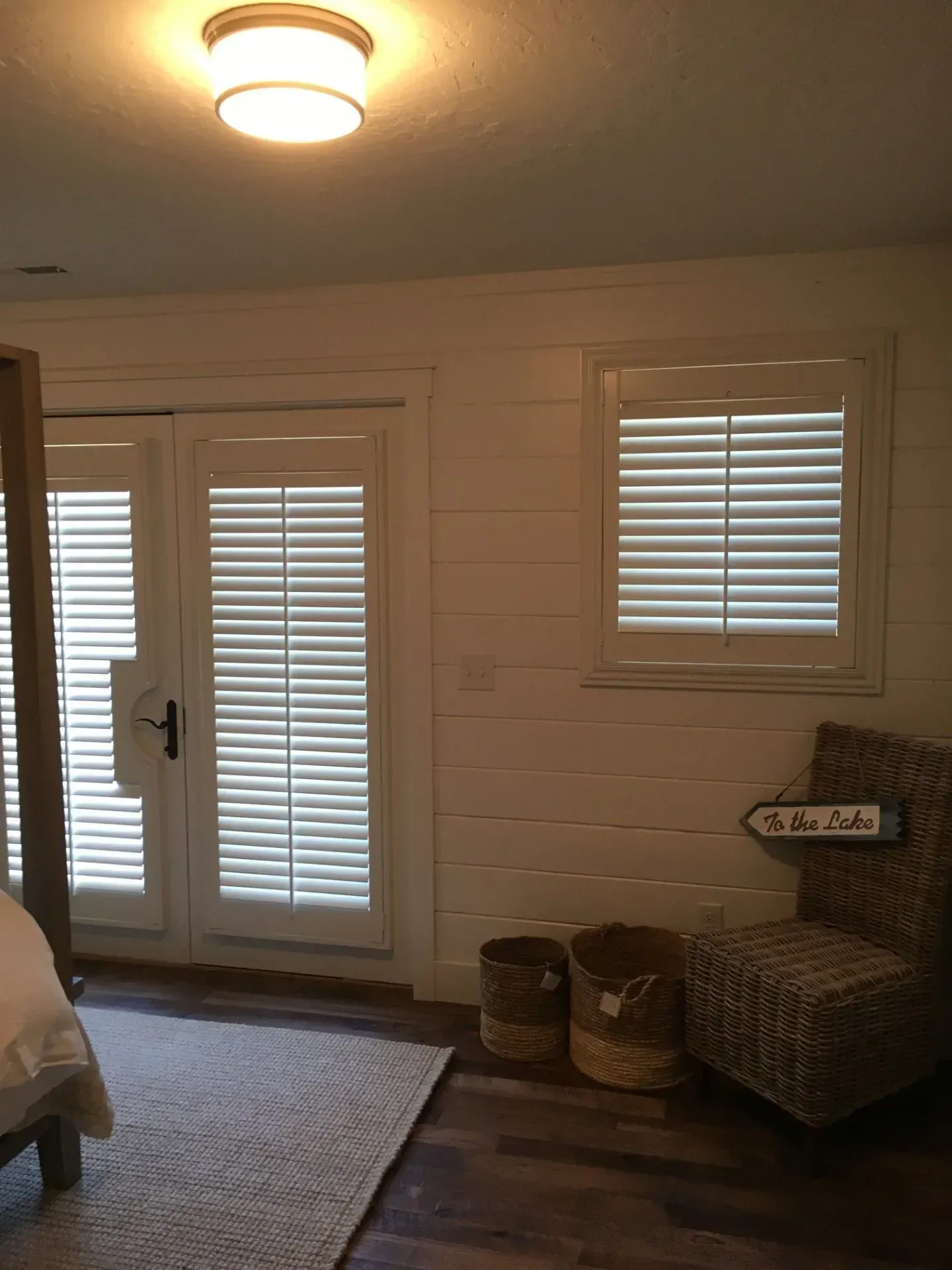 A bedroom with a bed, chair, and shutters on the windows.
