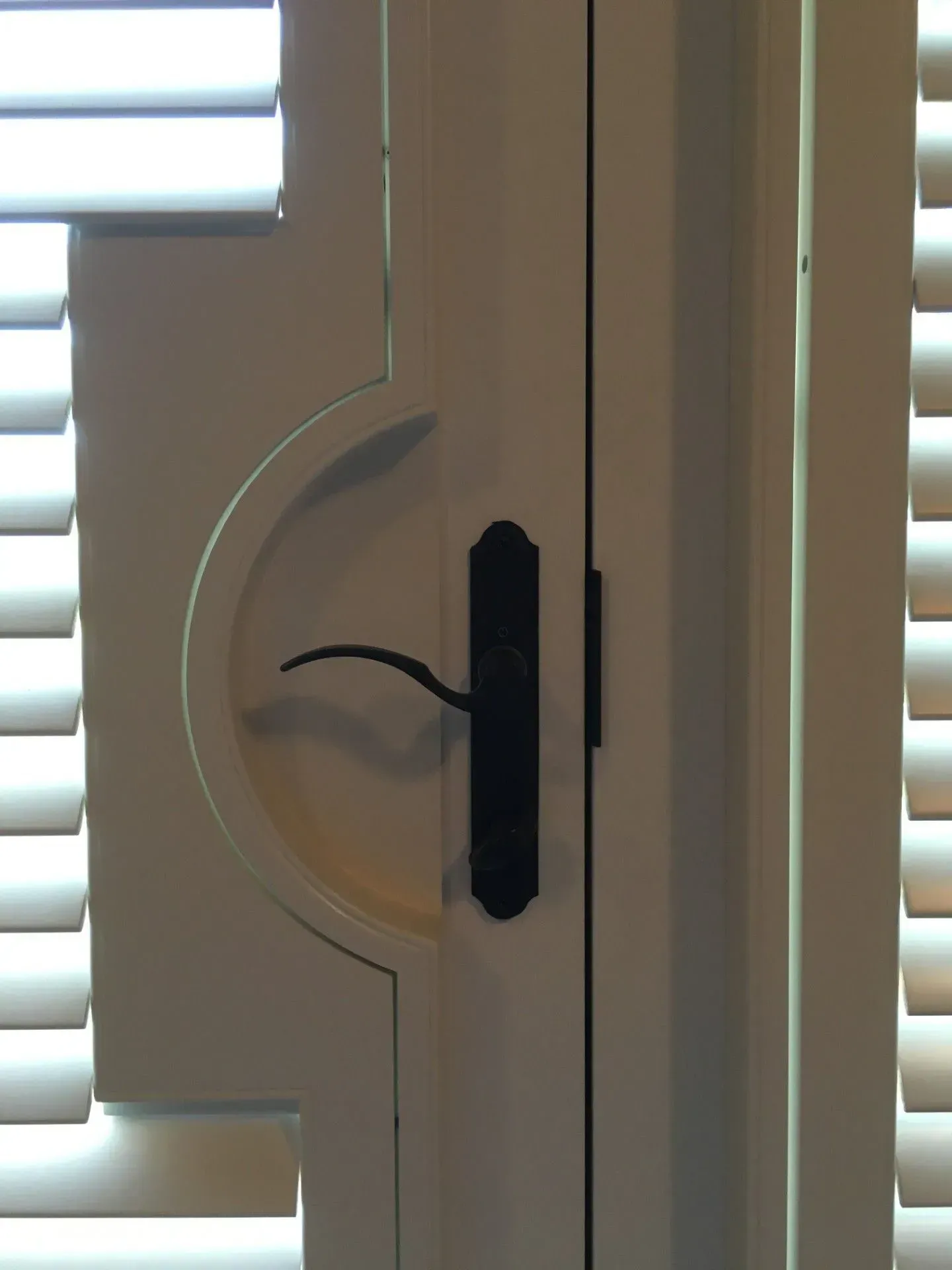 A white door with shutters and a black handle