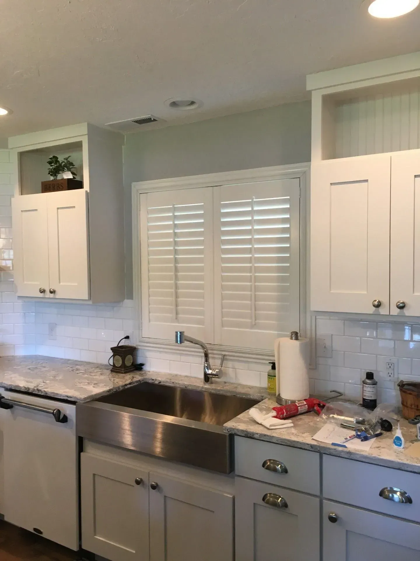 A kitchen with white cabinets and a stainless steel sink