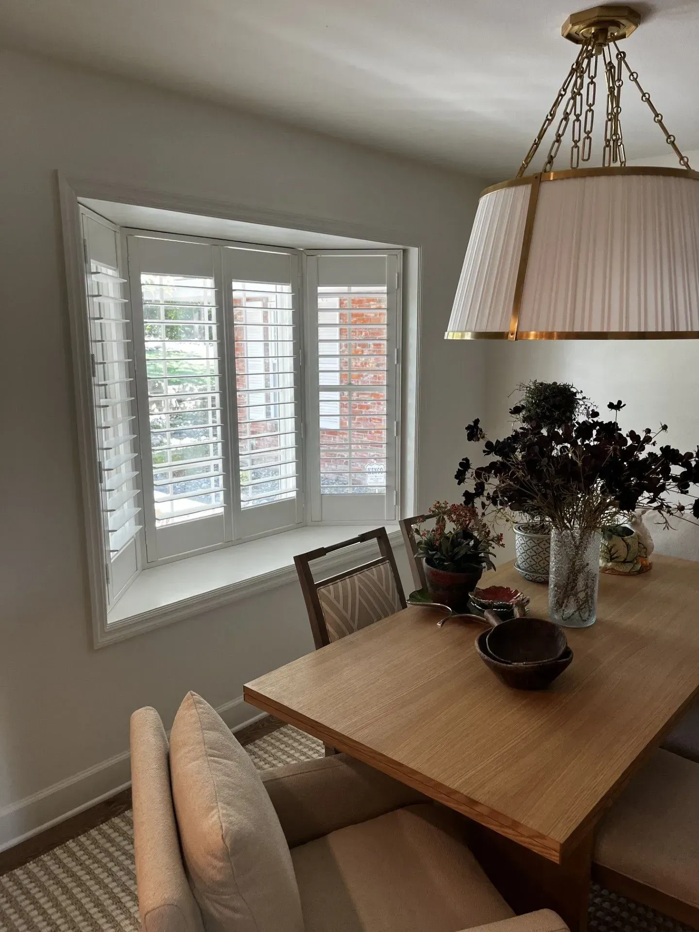 A dining room with a table and chairs and a window with shutters.