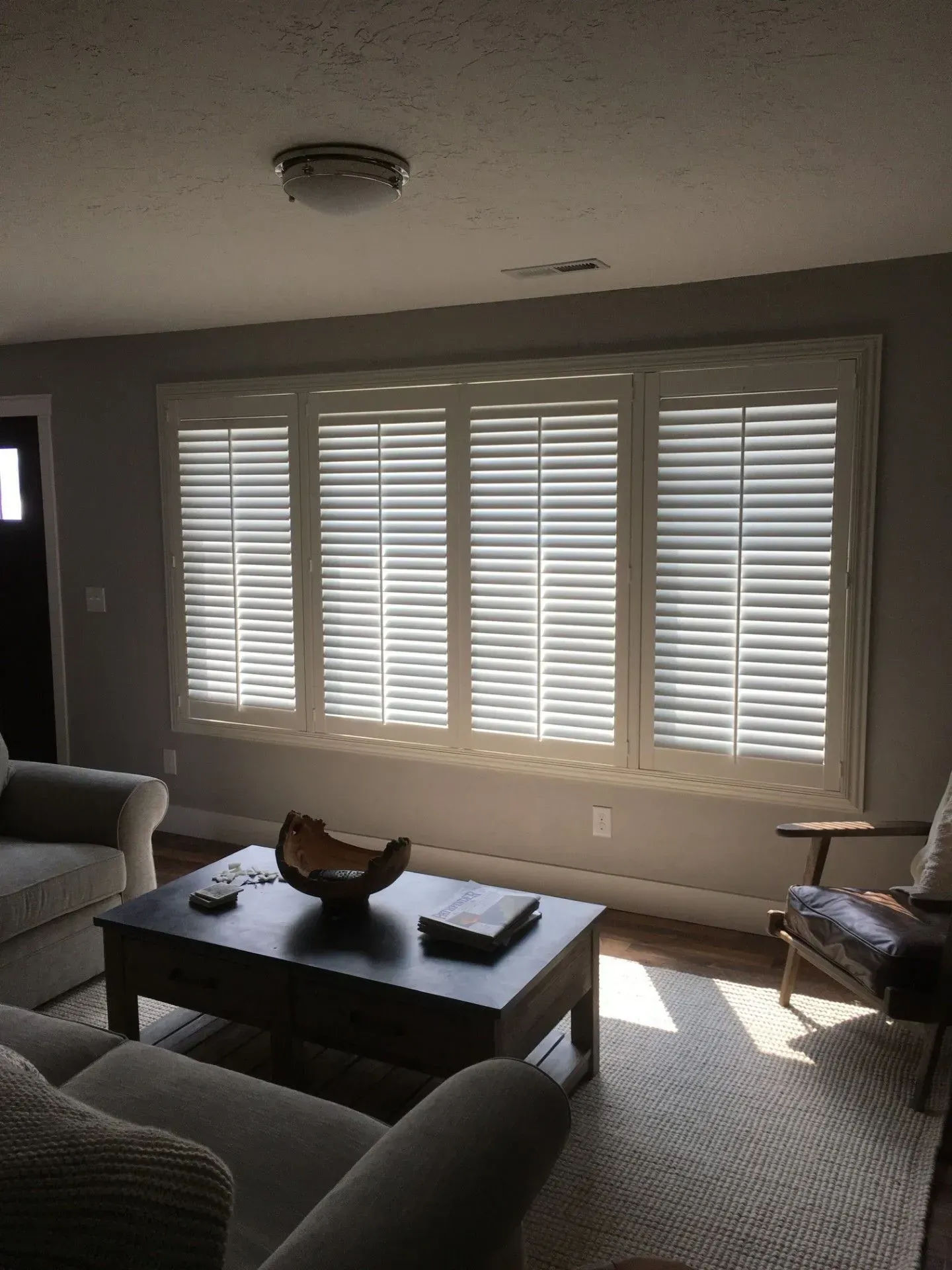 A living room with white shutters on the windows