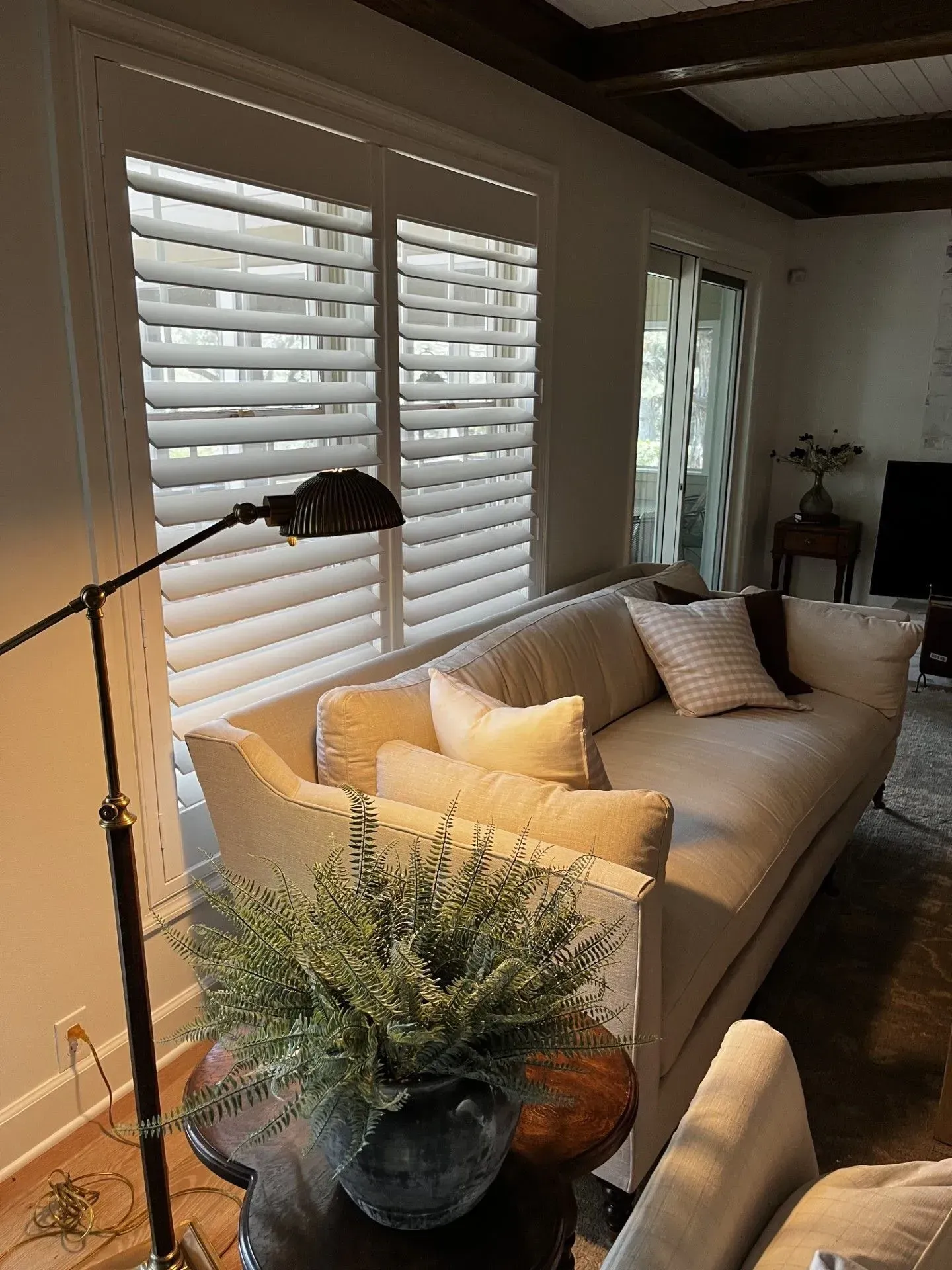 A living room with a couch and shutters on the windows.