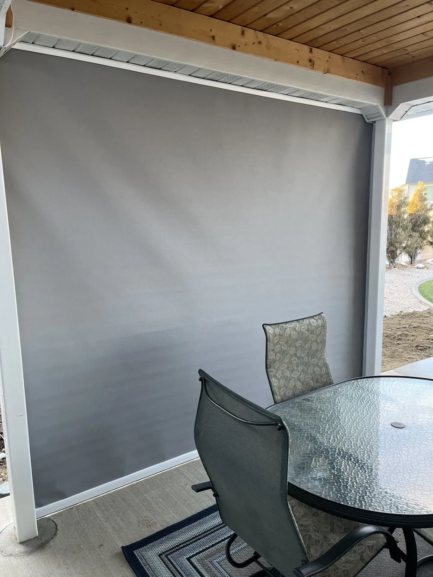 A patio with a table and chairs and a gray wall.