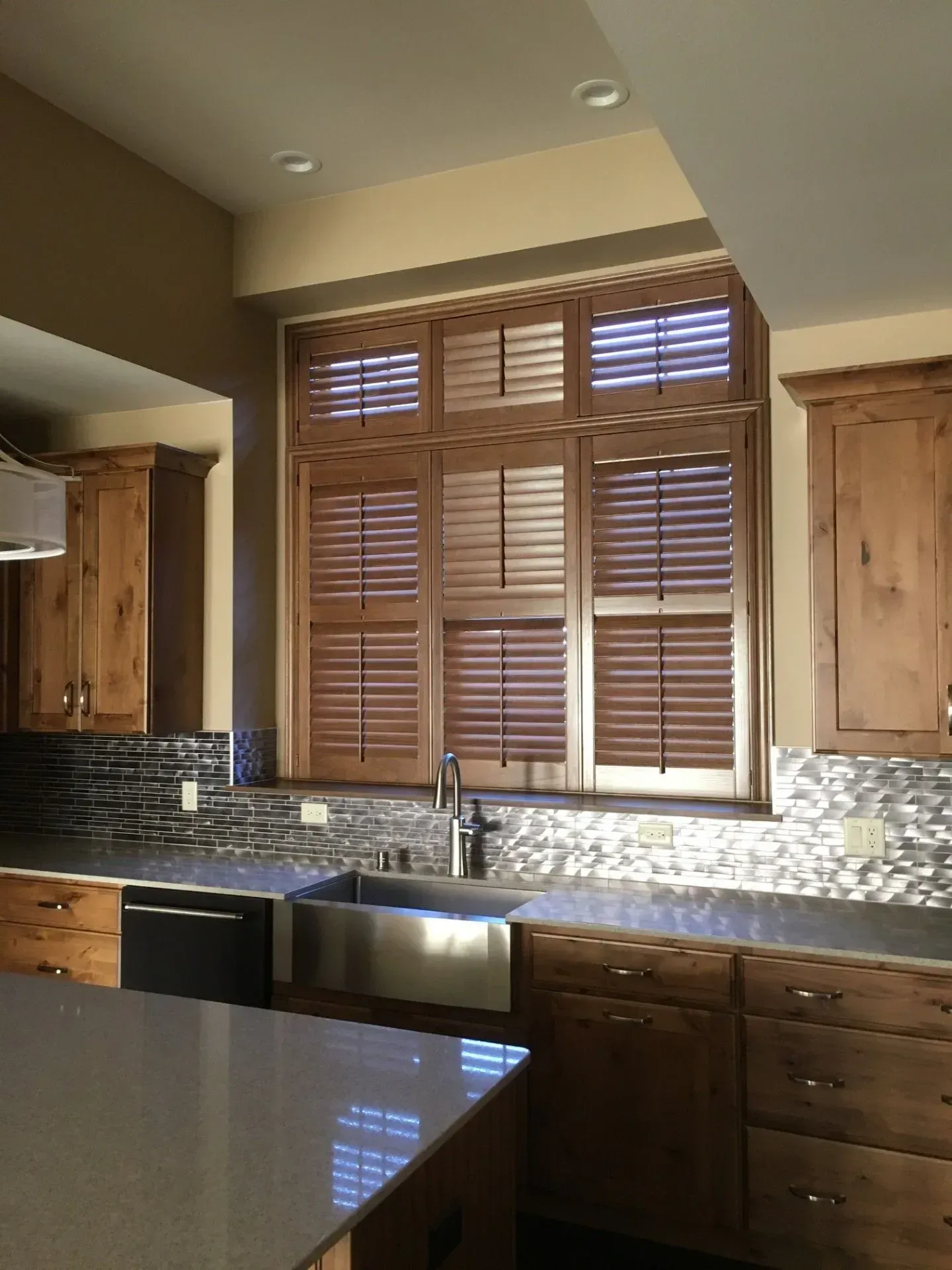 A kitchen with wooden cabinets and shutters on the windows