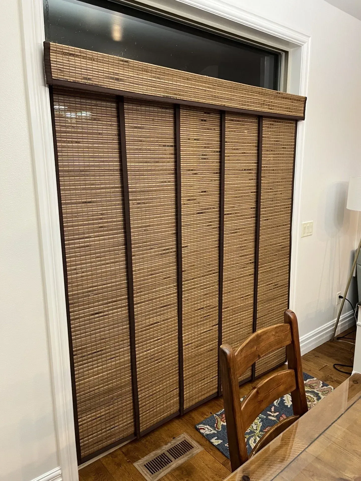 A dining room with a table and chairs and a window with blinds on it.