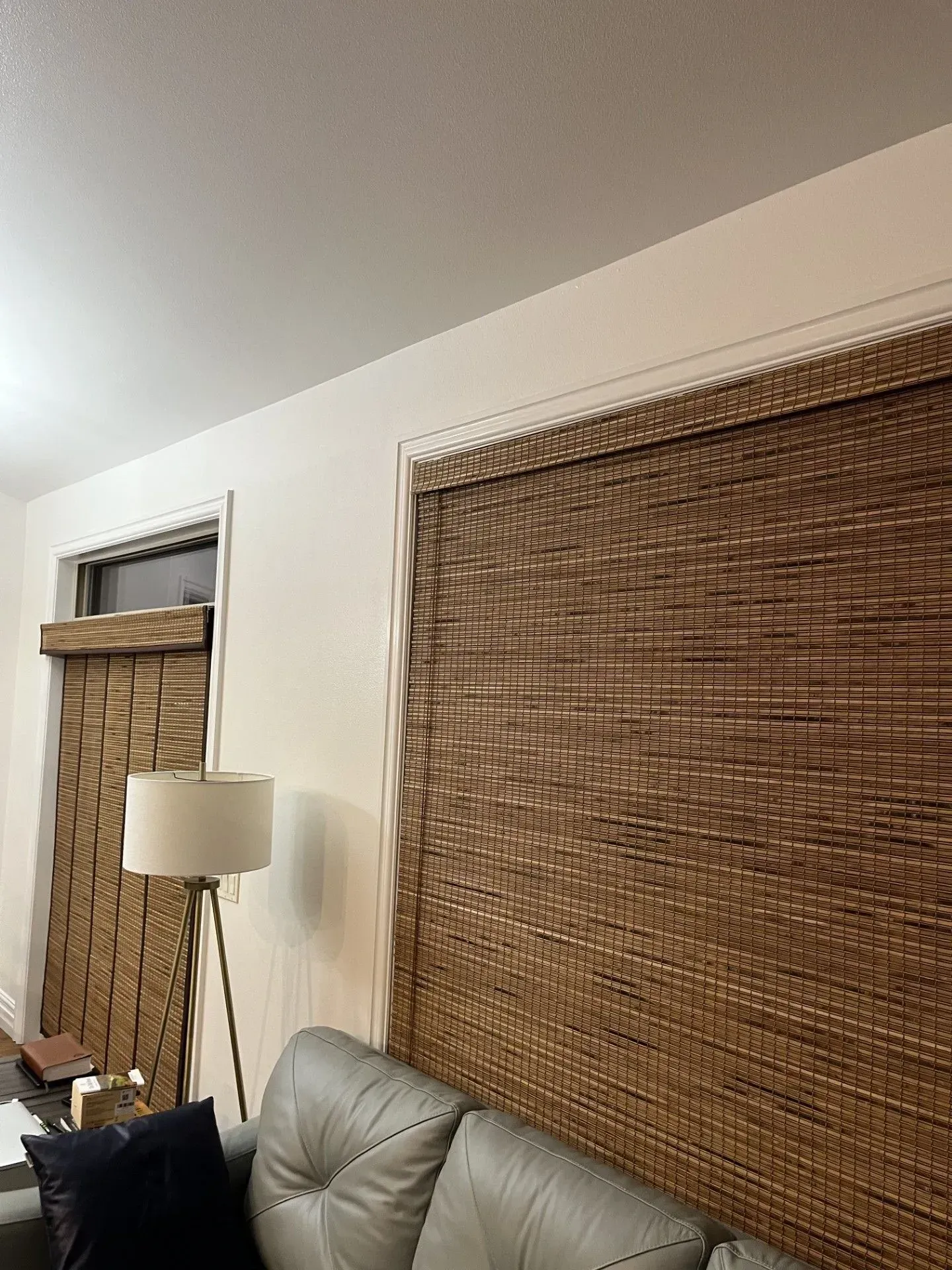 A living room with a couch, lamp, and blinds on the wall.