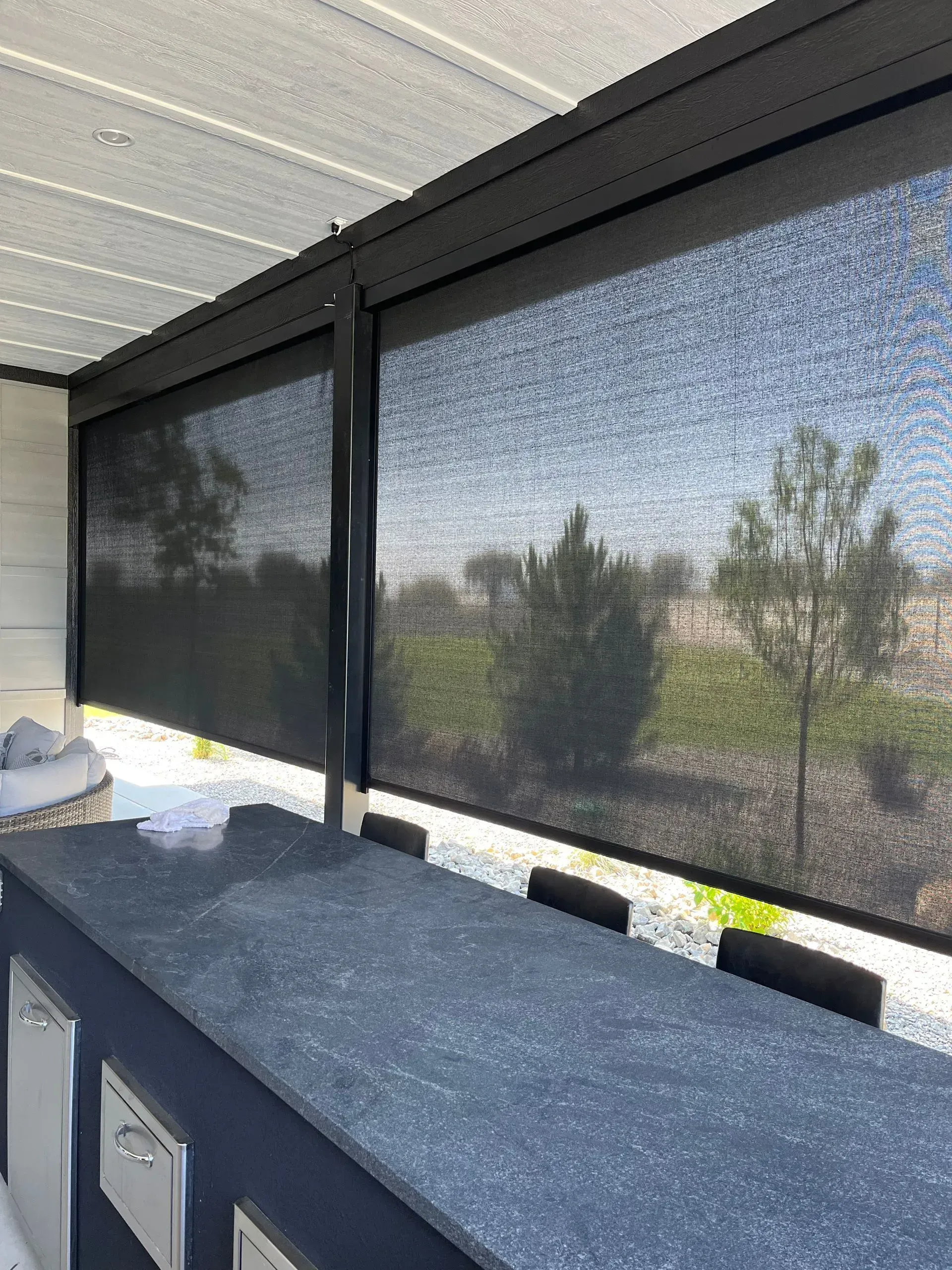 A kitchen with a counter top and a large window with shades on it.