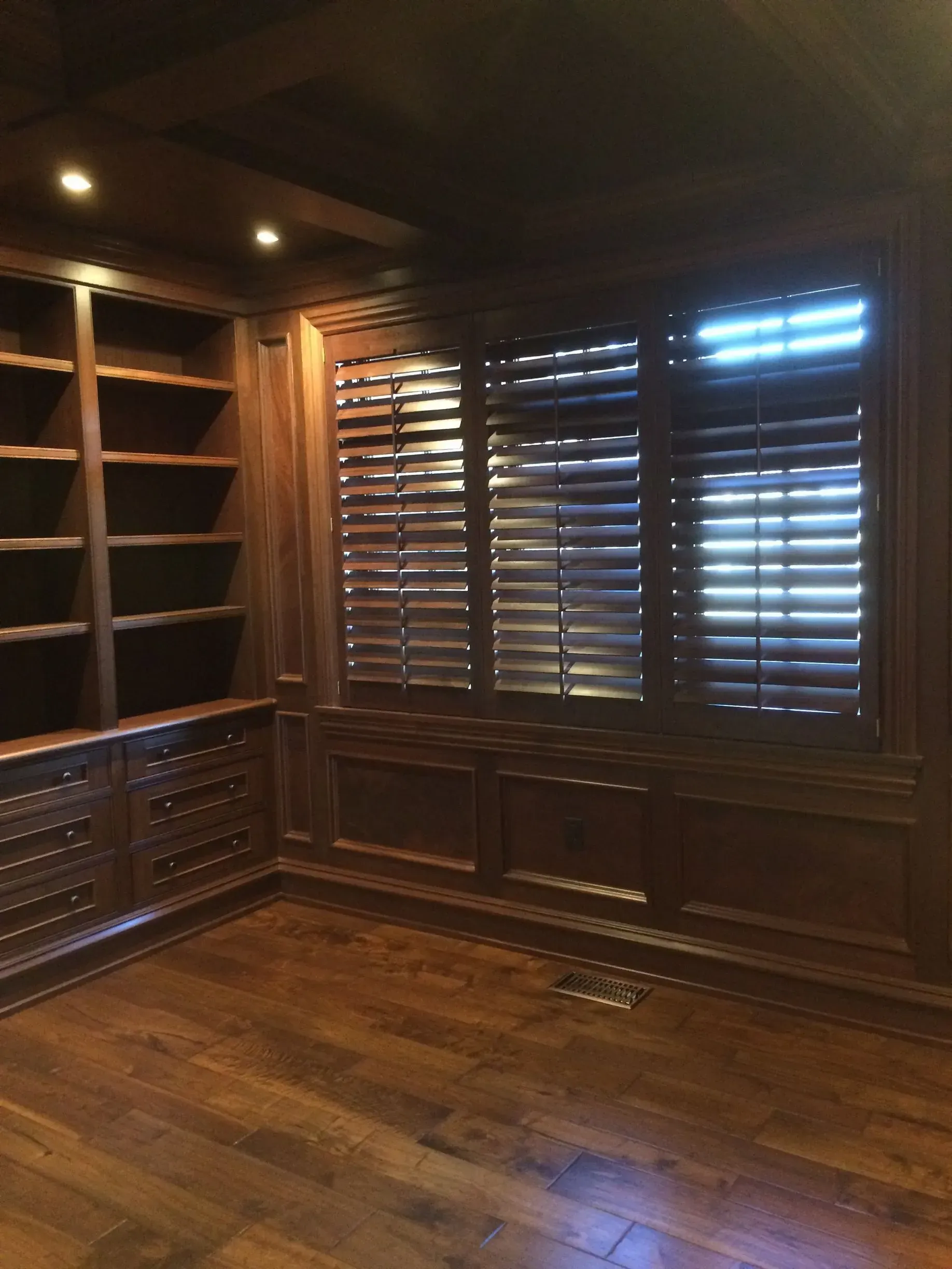 A room with wooden shelves and shutters on the windows