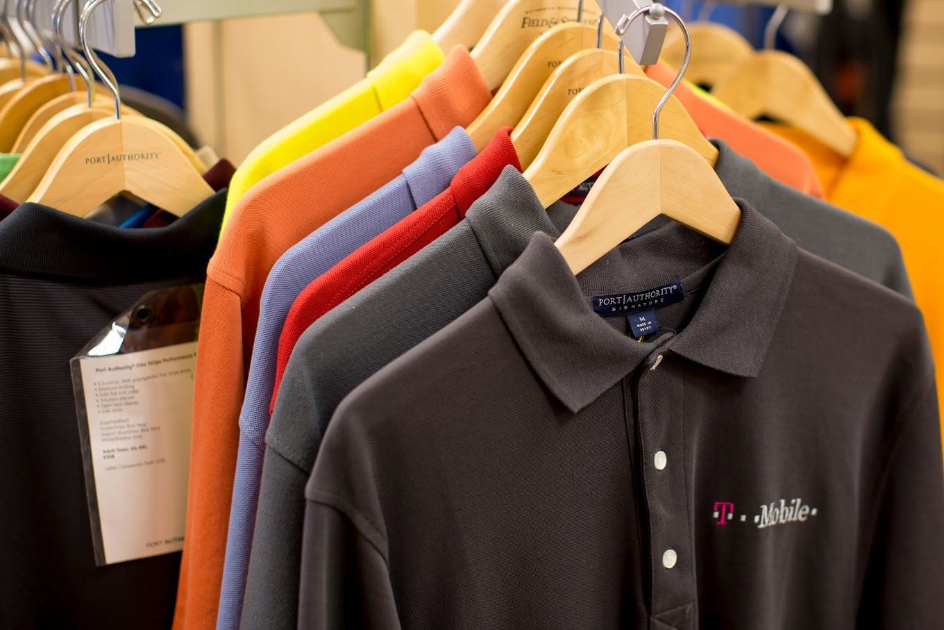 A Row of Colorful Polo Shirts Are Hanging on A Rack — Tempe, AZ — Big Stitch Embroidery