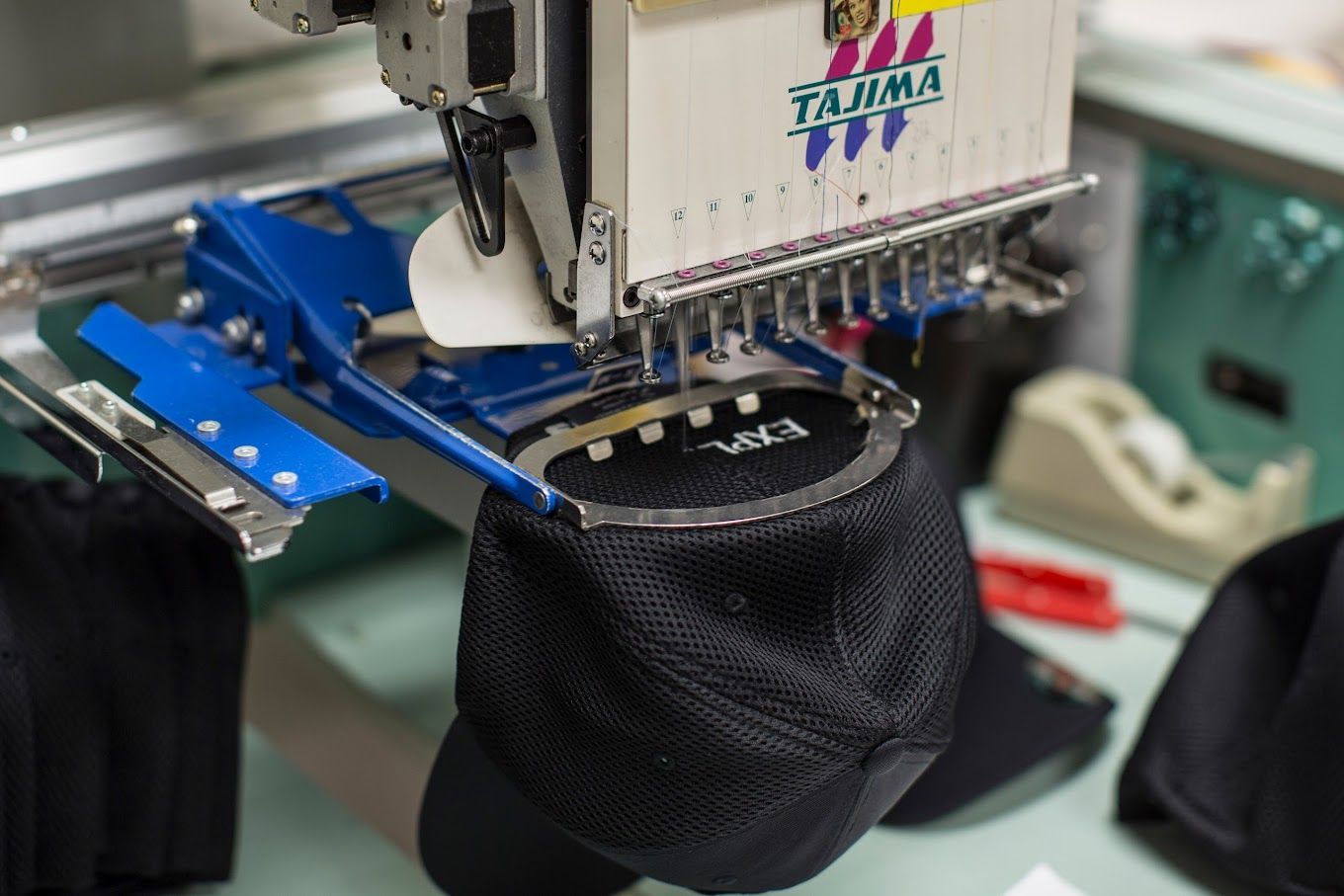 A Hat Is Being Embroidered on A Machine in A Factory — Tempe, AZ — Big Stitch Embroidery