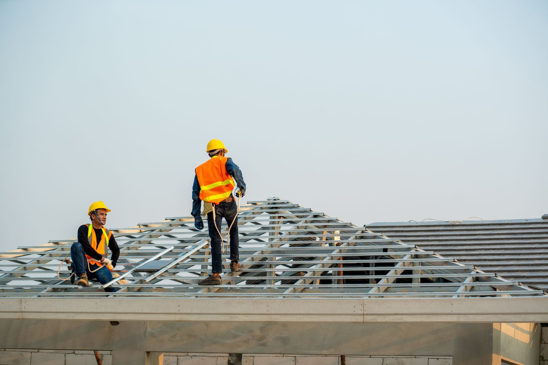 Two construction workers installing metal roofing panels on a building frame Two construction workers installing metal roofing panels on a building frame