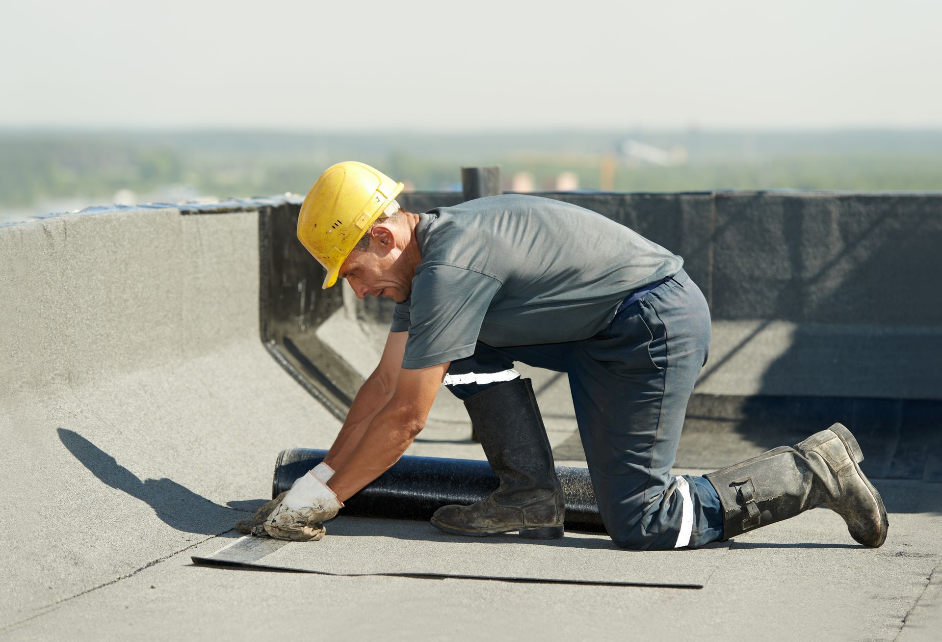 A commercial roofing contractor is preparing part of a bitumen roofing felt roll for melting.