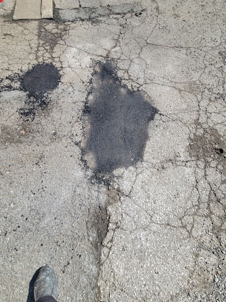 A person is standing on a cracked asphalt road.