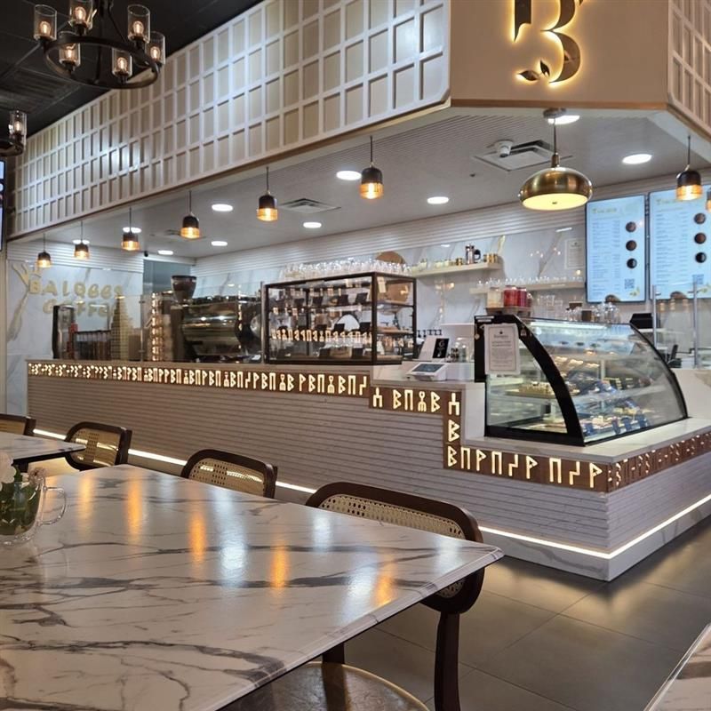 Interior view of a modern cafe with a marble countertop, coffee machines, and hanging lights.